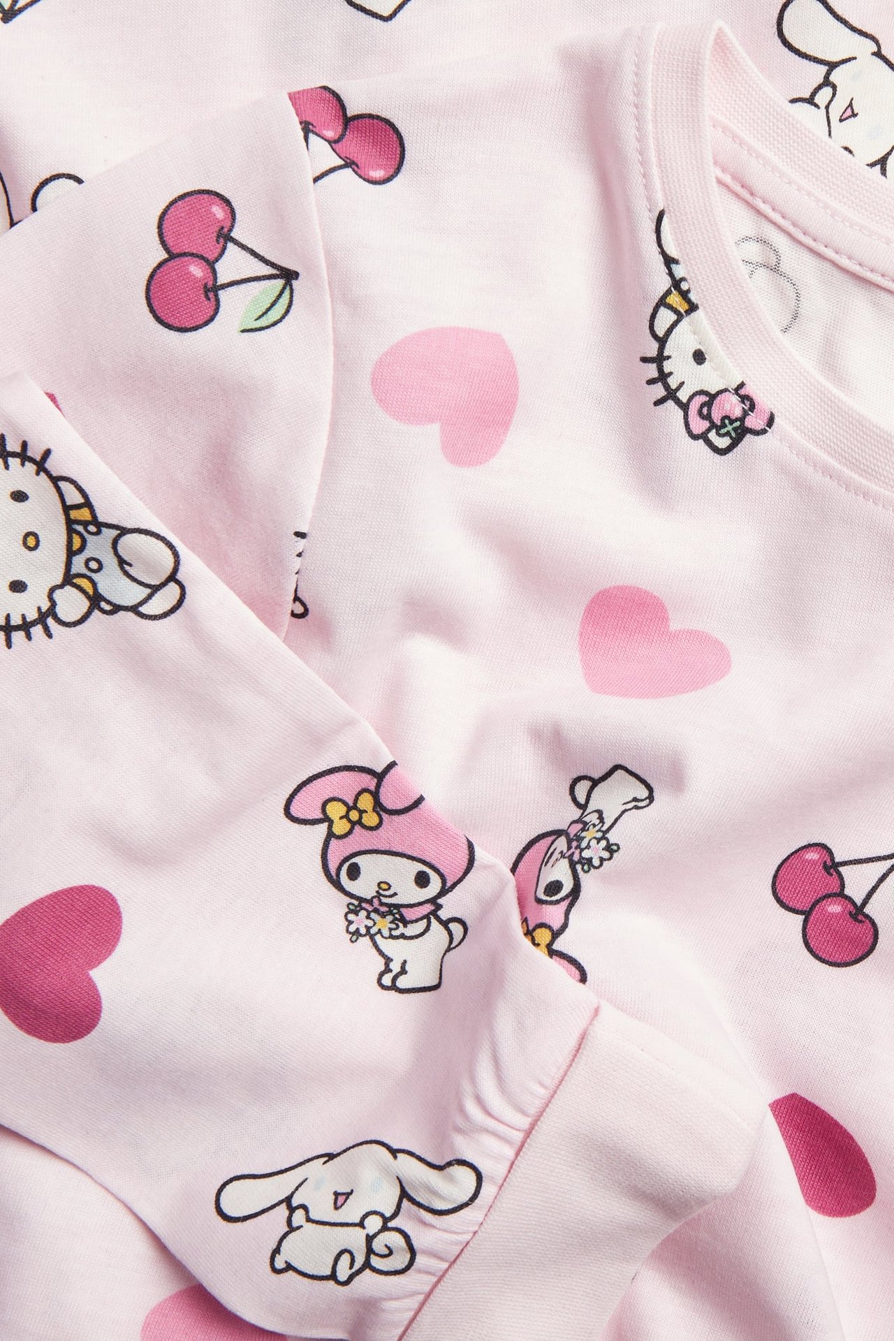 Lähikuva vaaleanpunaisesta Sanrio-hahmopainetusta pyjamapaidasta, jossa sydämiä ja kirsikoita.