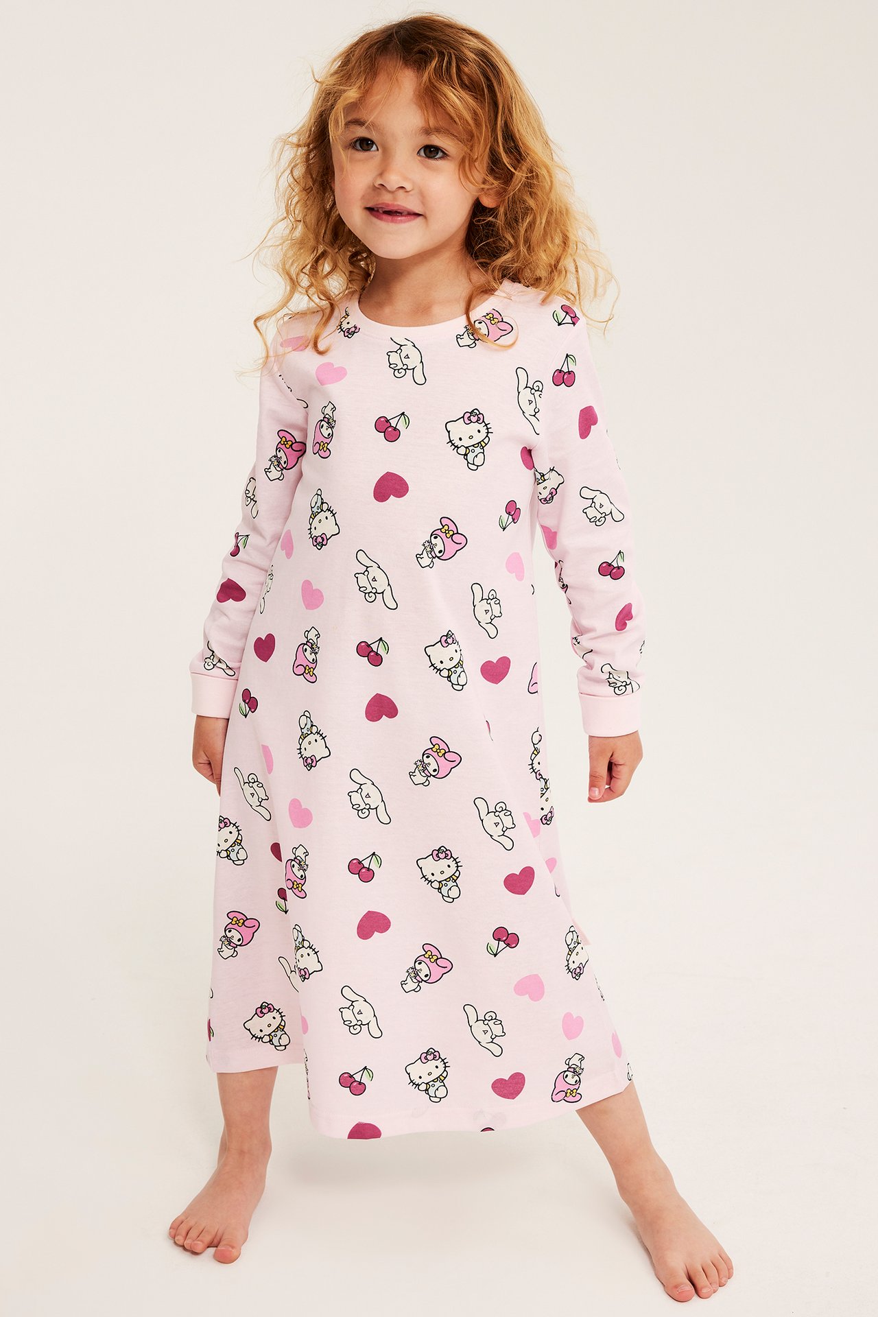 Frontvy av ett barn i ett rosa långärmat nattlinne med Hello Kitty-tryck.
