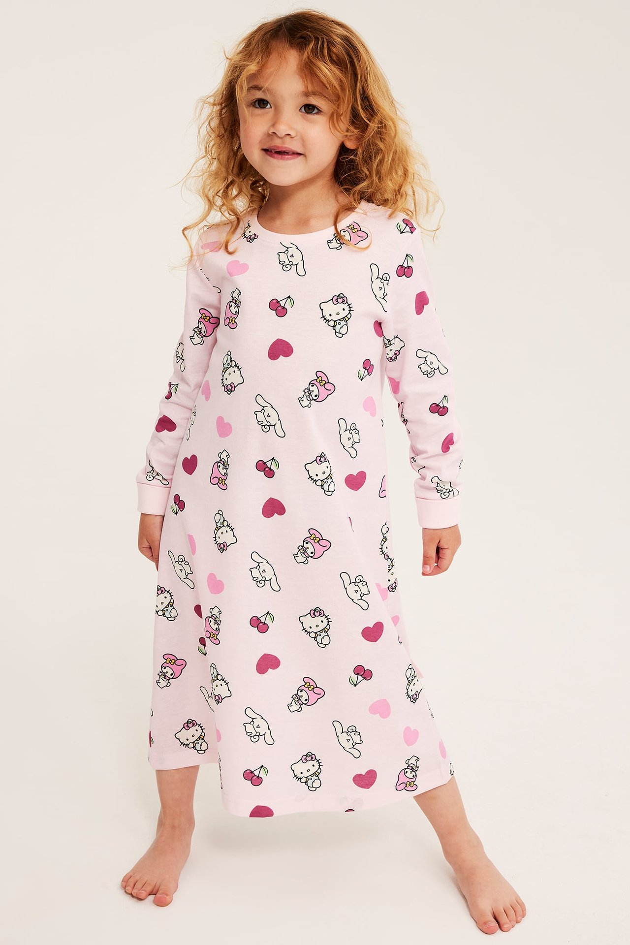 Edestäpäin näkymä lapsesta vaaleanpunaisessa pitkähihaisessa Hello Kitty -yöpaidassa.
