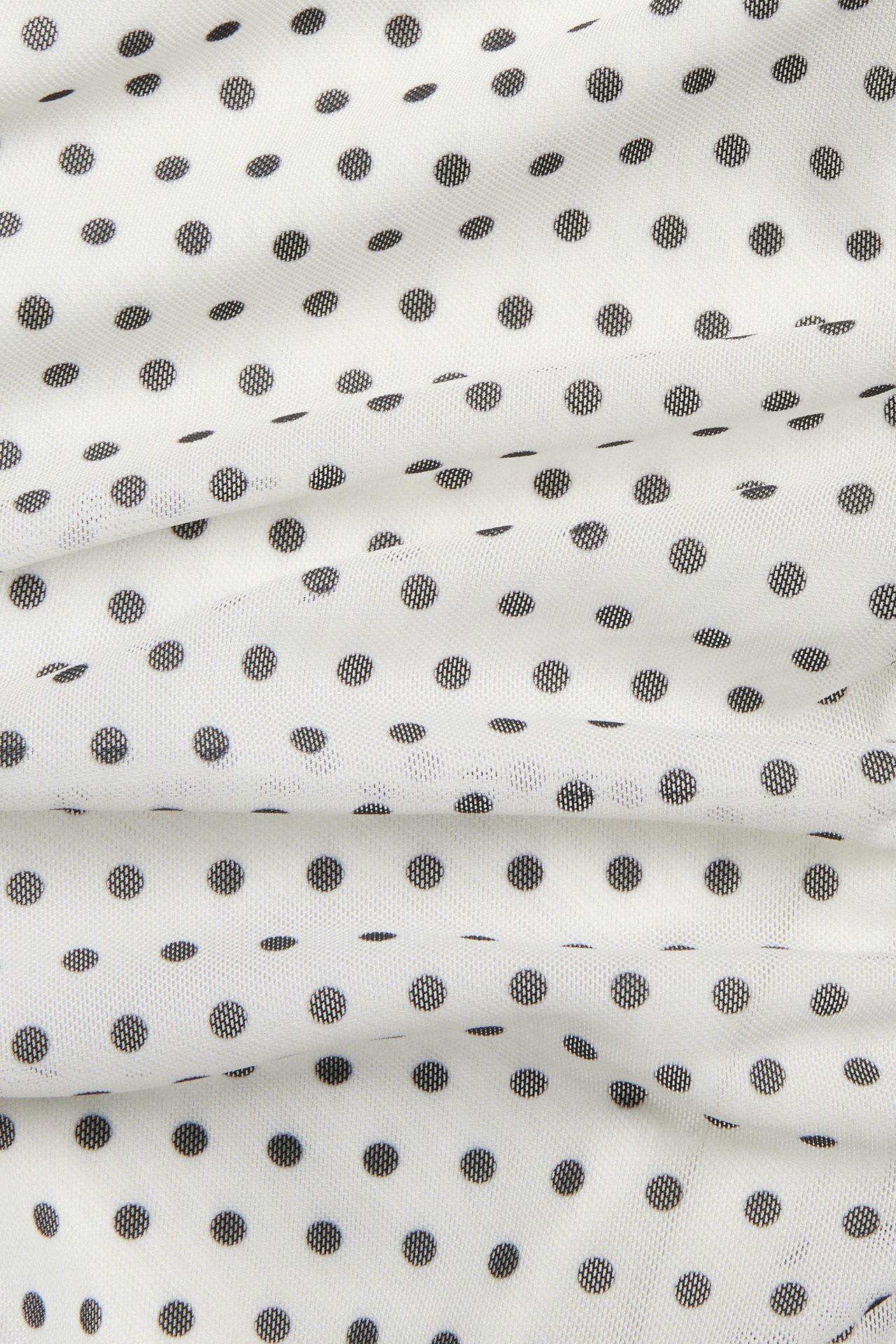 Närbild av offwhite meshklänning med svarta prickar och rynkade detaljer.
