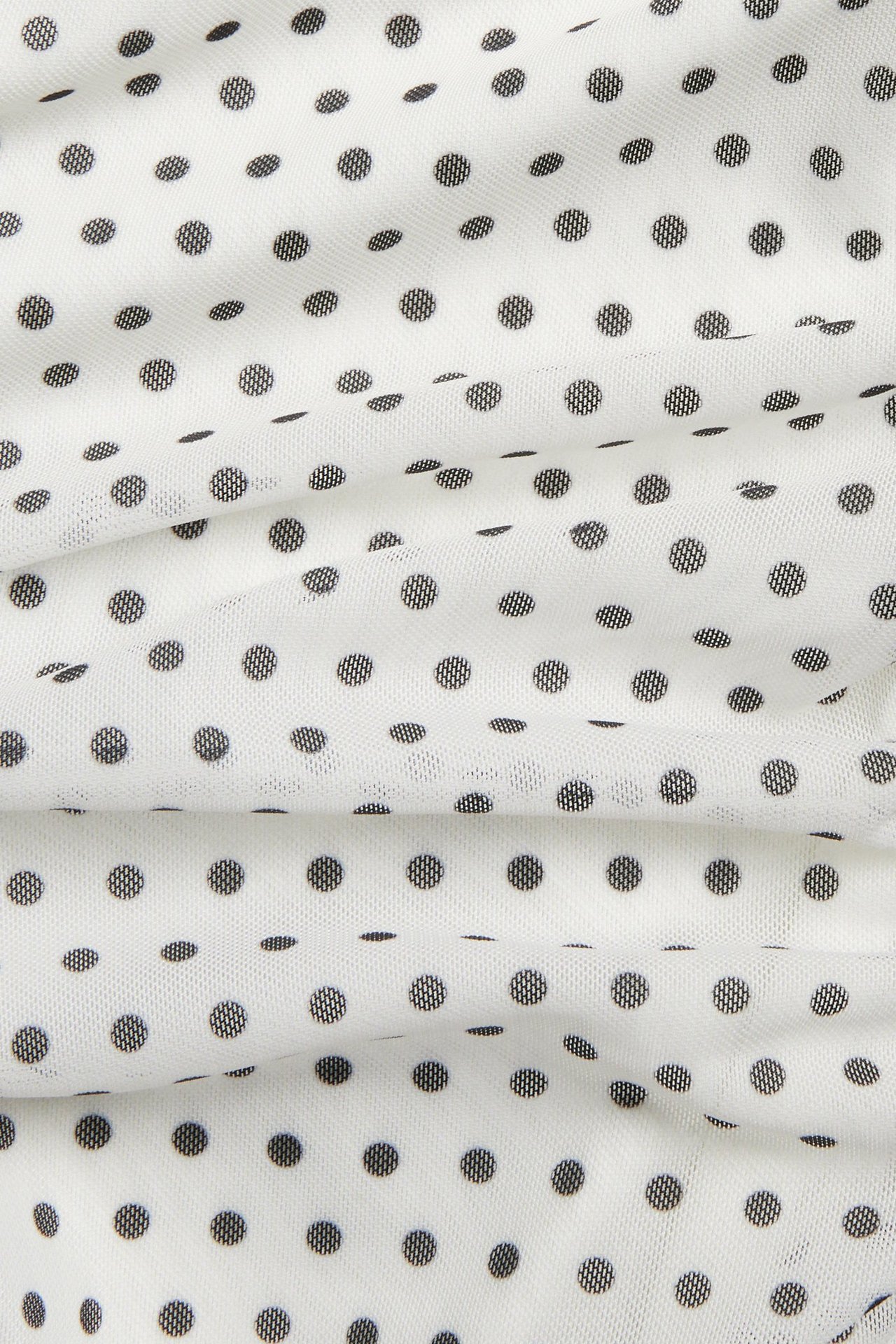 Närbild av offwhite meshklänning med svarta prickar och rynkade detaljer.