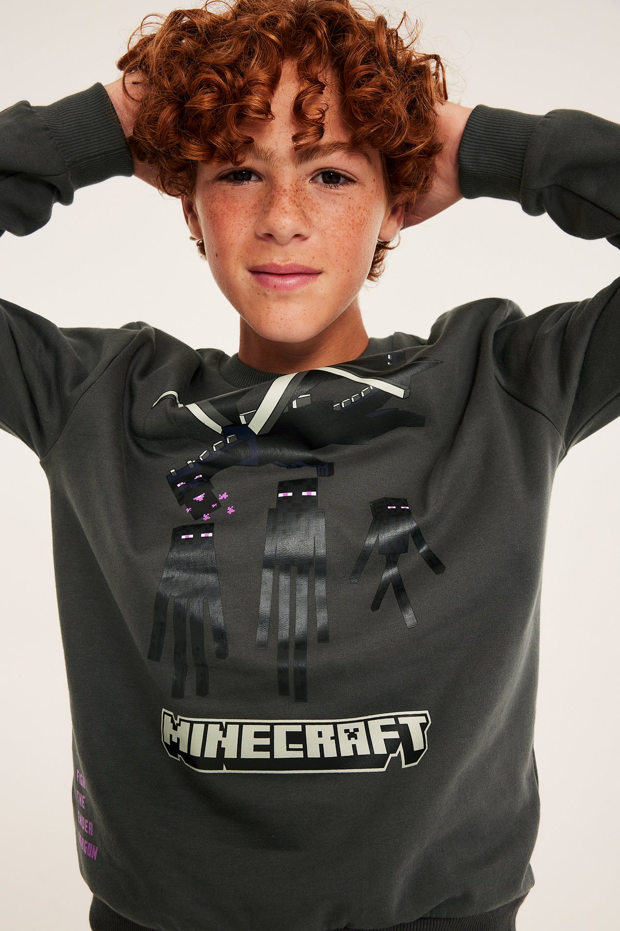 Framifrån, ett barn i en mörkgrå långärmad sweatshirt med Minecraft-tryck.