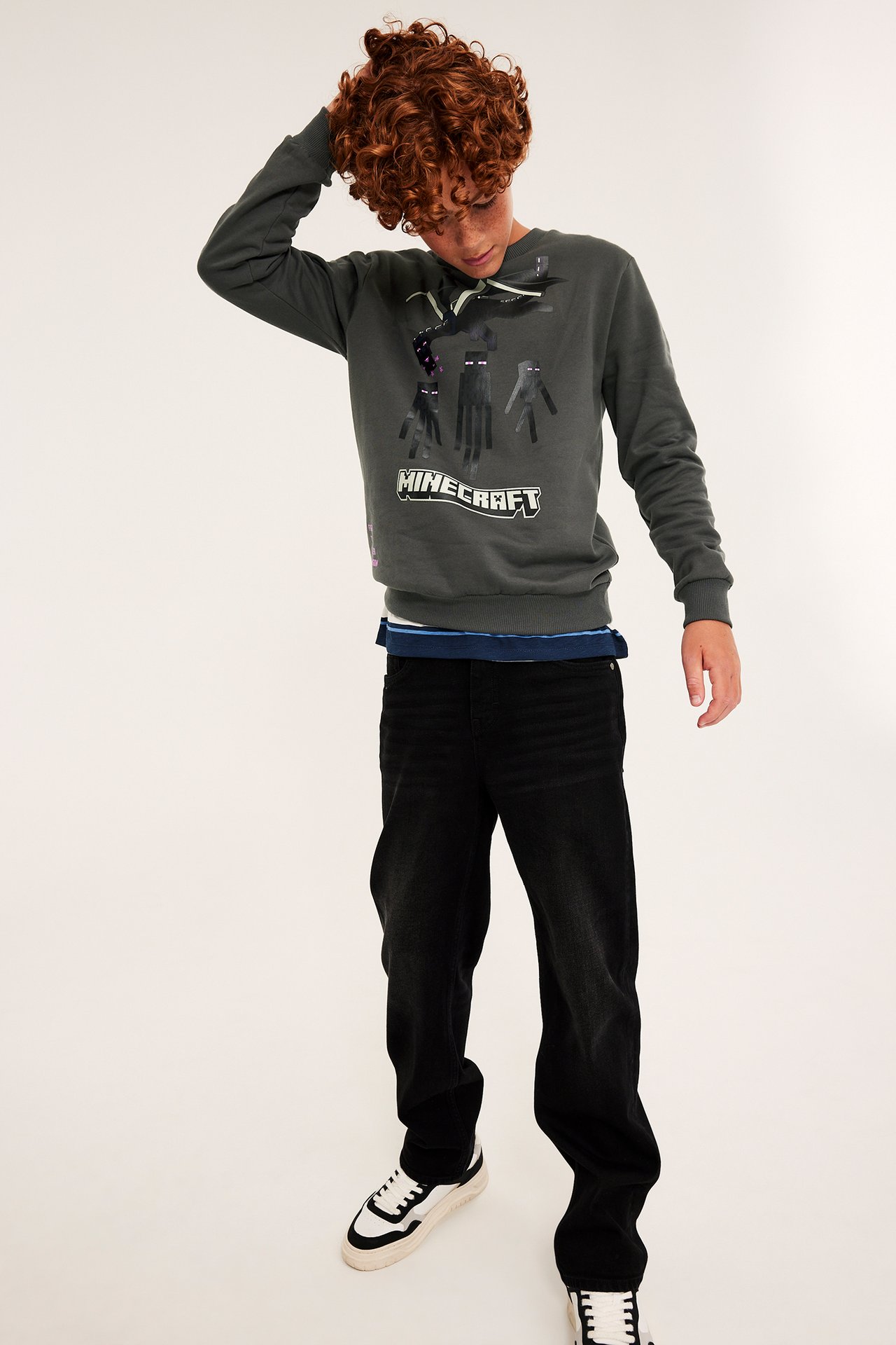 Framsida av barn med mörkgrå Minecraft-tröja, svarta jeans och svartvita sneakers.