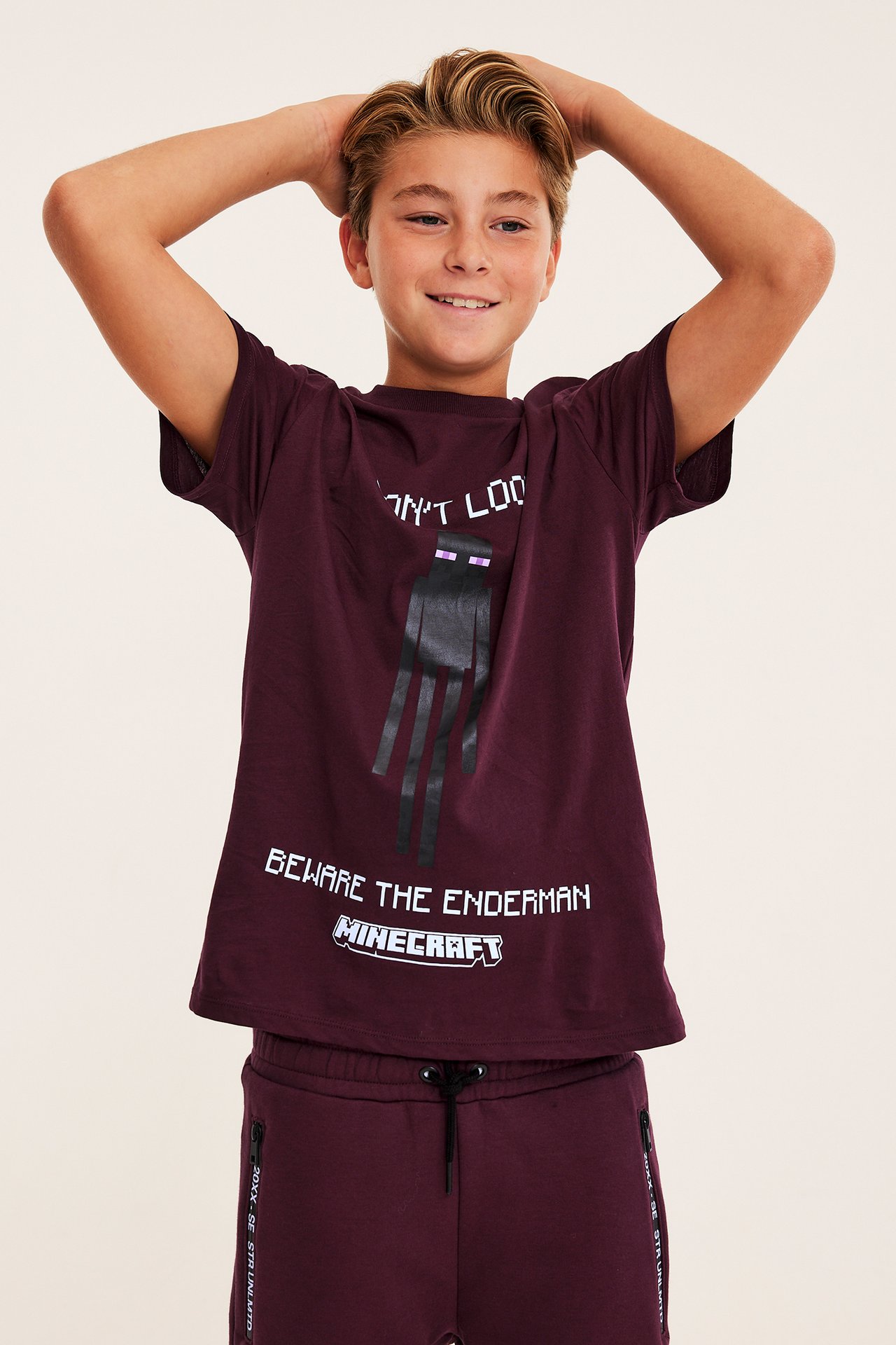 Framifrån, barn i vinröd Minecraft Enderman-tryckt t-shirt och matchande vinröda sweatpants.