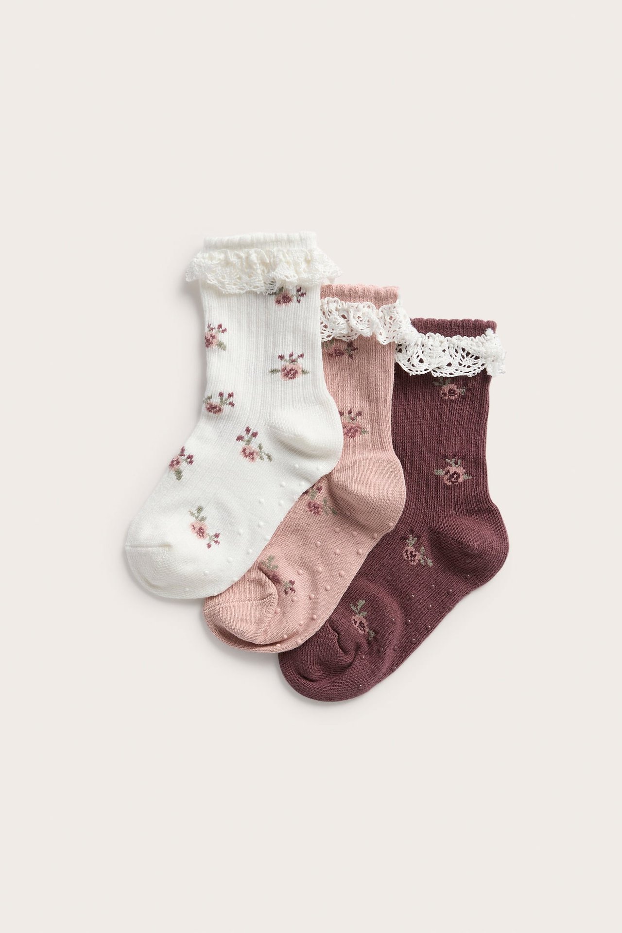Kolme paria lasten kukkasukkia pitsireunalla: valkoinen, pinkki ja viininpunainen.