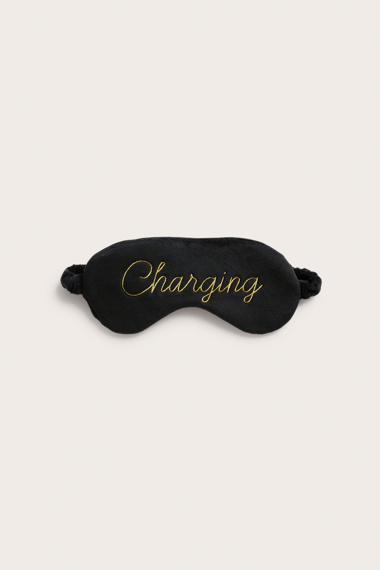 Musta unimaski, jossa 'Charging' kirjailtu kullalla, ylhäältä.