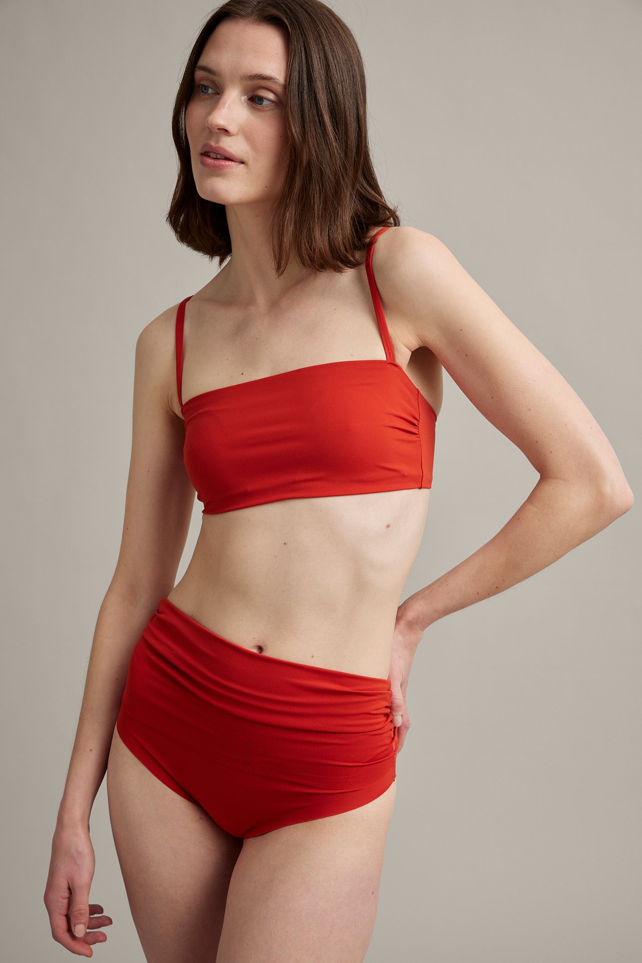 Forfra: kvinne i rød bikinitruse med nedbrettbar midje og matchende rød bandeau bikinitopp.