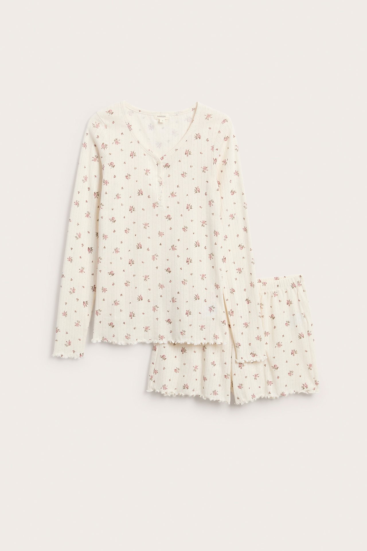 Framsida av ett benvitt ribbat blommigt pyjamasset med långärmad topp och volangkantade shorts.