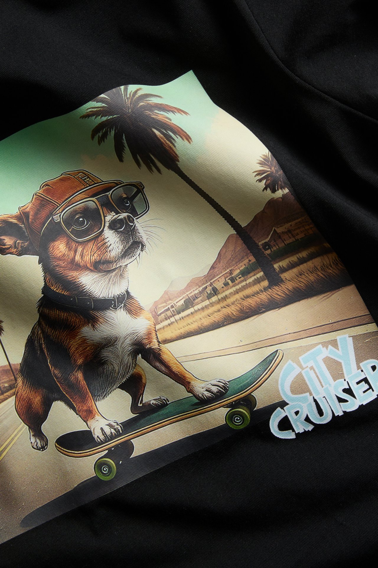 Lähikuva mustasta puuvilla-t-paidasta, jossa on printti edessä rullalautailevasta chihuahuasta ja 'CITY CRUISER' -teksti.