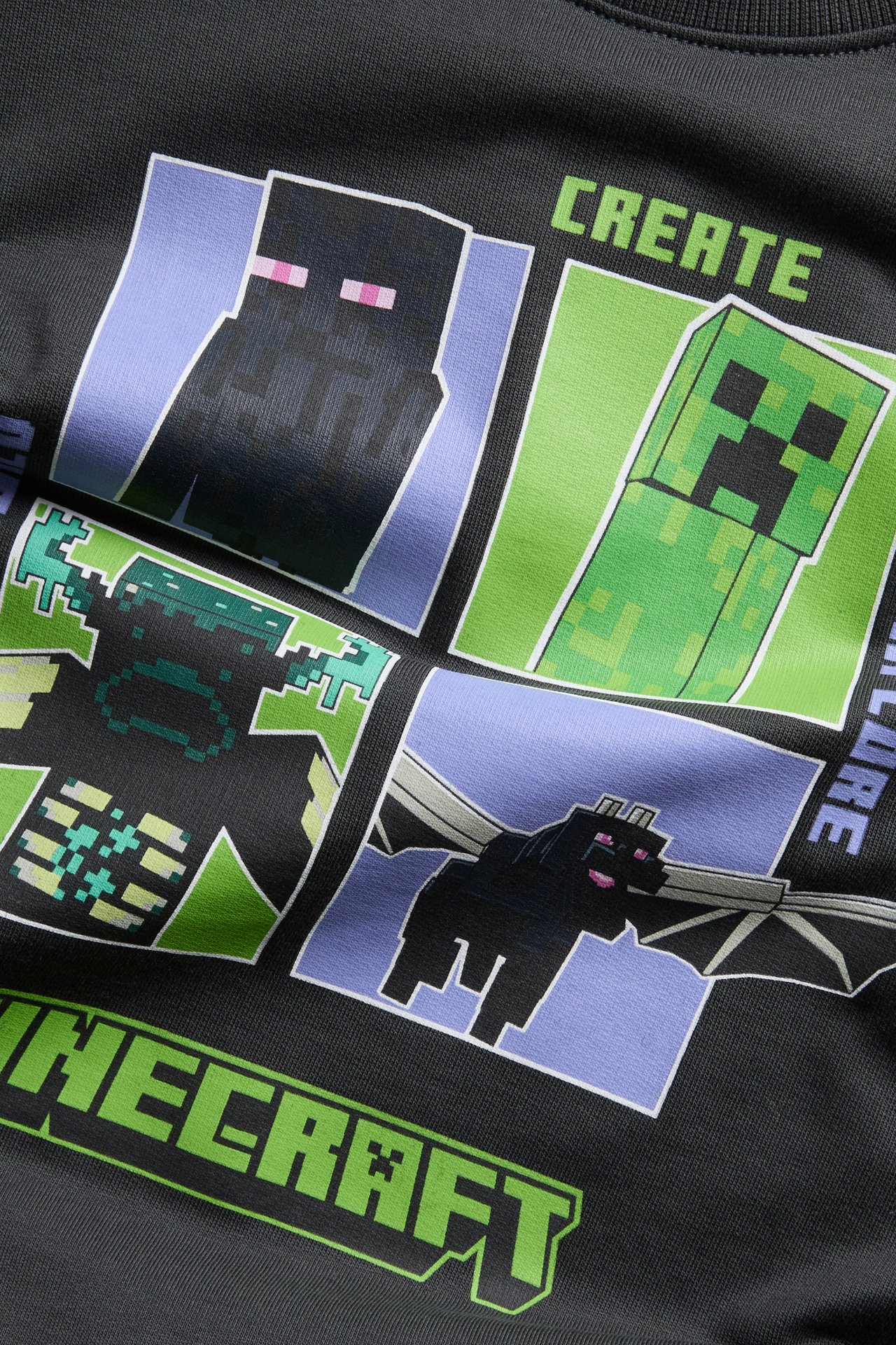Nærbilde av en mørkegrå genser med et Minecraft-karaktertrykk og tekst.
