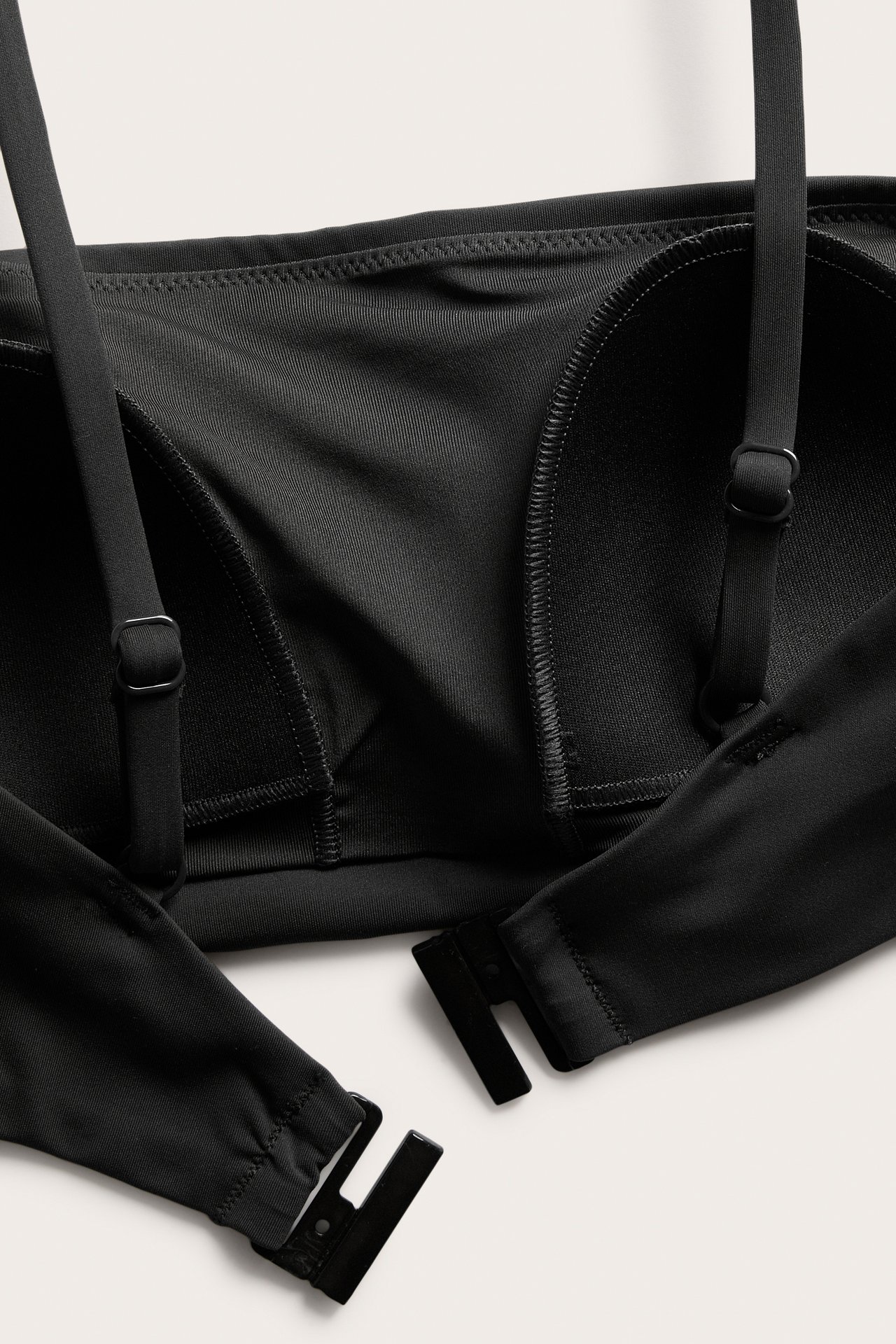 Lähikuva mustasta topatusta bandeau-bikiniliivistä säädettävillä olkaimilla ja takakiinnityksellä.