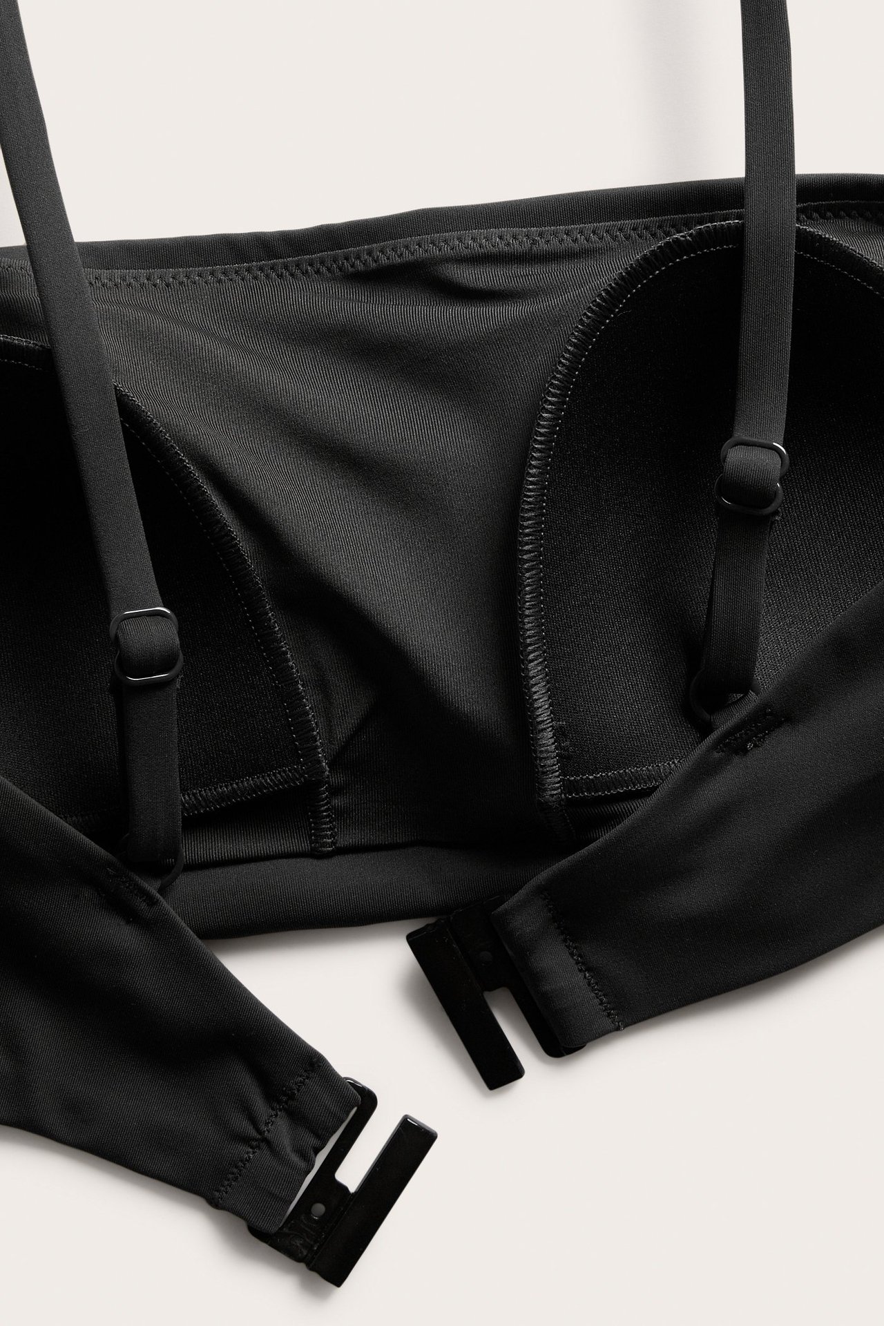 Lähikuva mustasta topatusta bandeau-bikiniliivistä säädettävillä olkaimilla ja takakiinnityksellä.