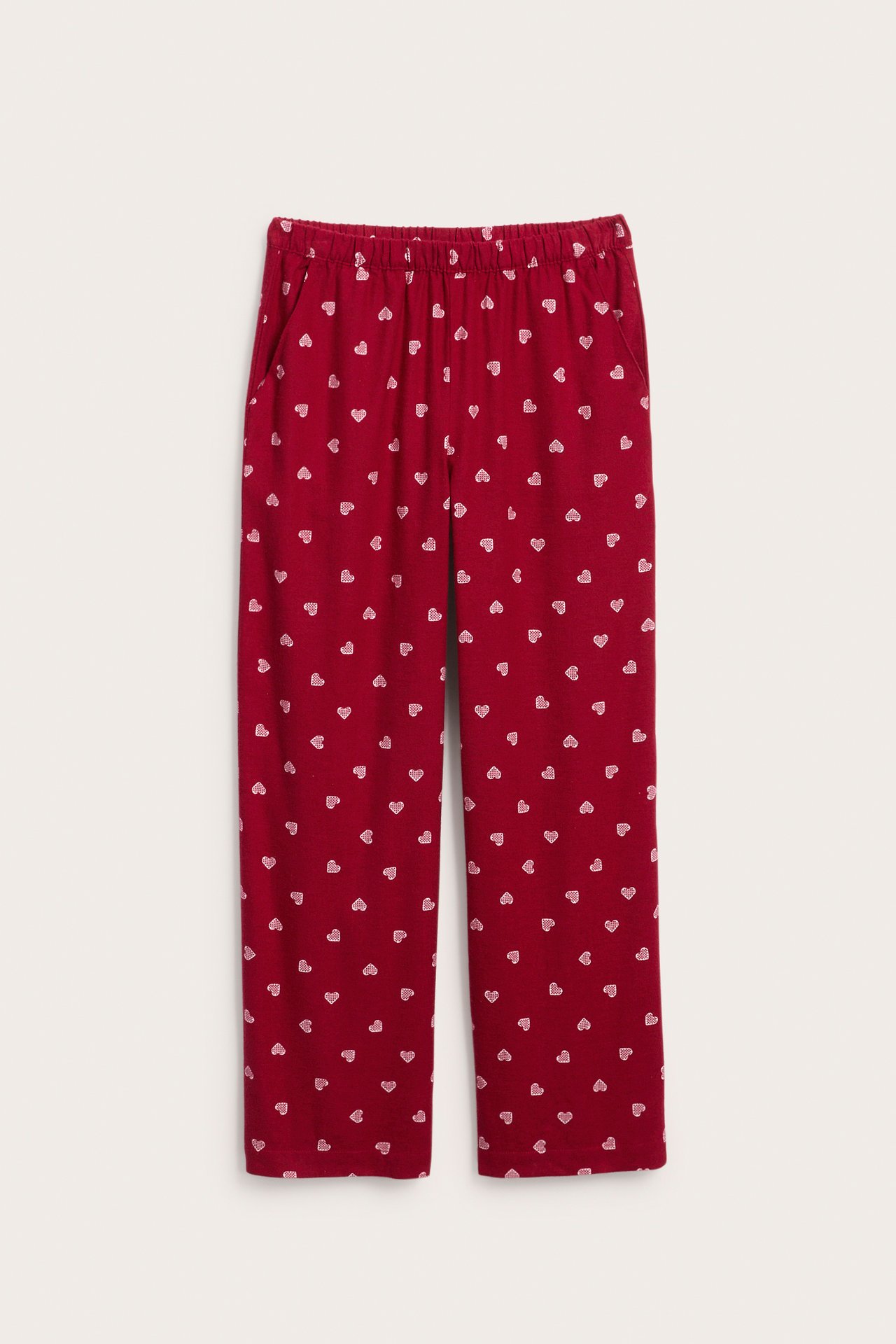 Frontvy av röda pyjamasbyxor med vitt hjärtmönster och elastisk midja.