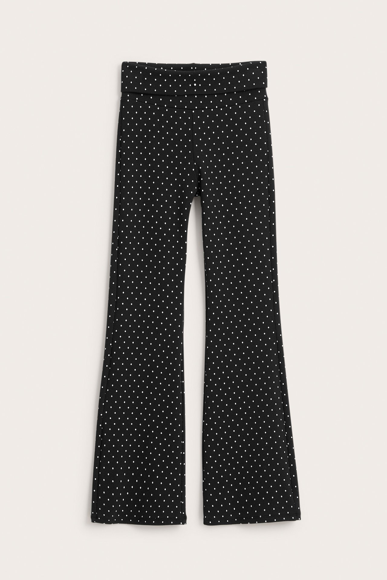 Widok z przodu czarnych legginsów typu flare w białe kropki z zakładanym pasem.