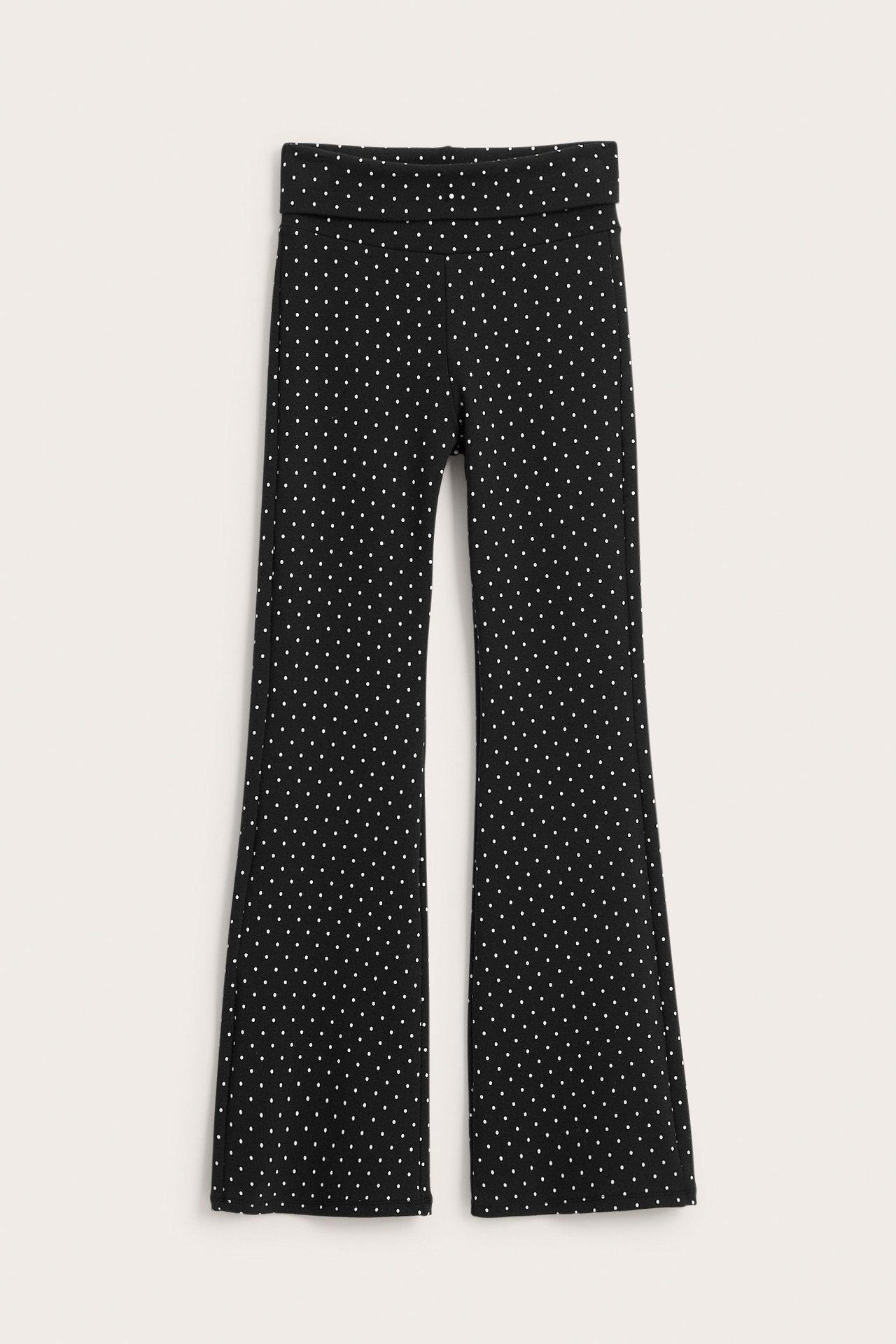 Edestä, mustat leveälahkeiset leggingsit valkoisilla pilkuilla ja taitettavalla vyötäröllä.