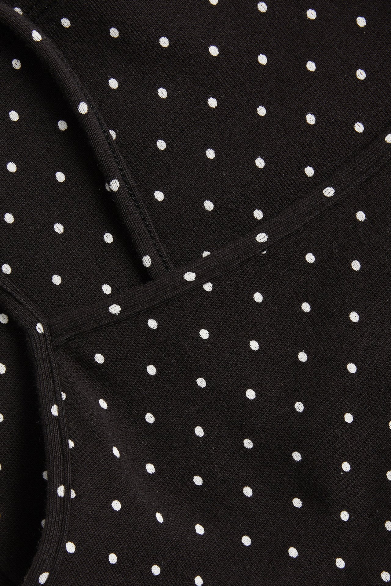 Nærbilde av en svart bomullstopp med hvite prikker og smale skulderstropper.