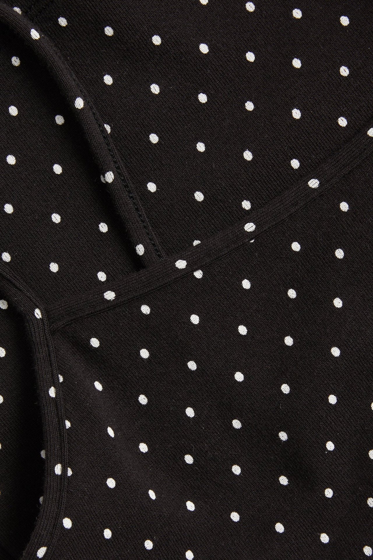 Närbild av ett svart prickigt linne i bomullstrikå med smala axelband.