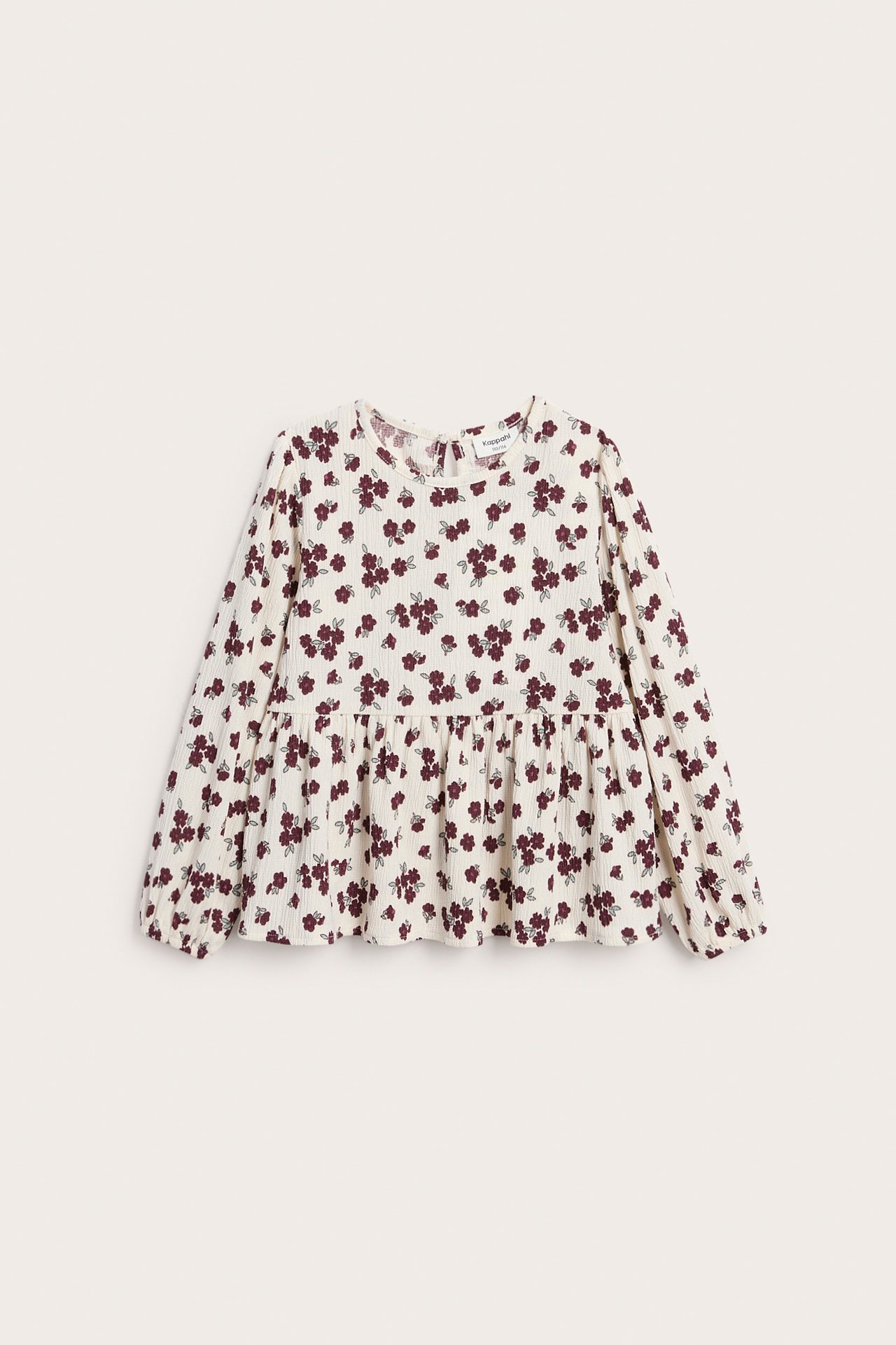 Framifrån, en vit barnblus med långa ärmar och vinröda blommor.