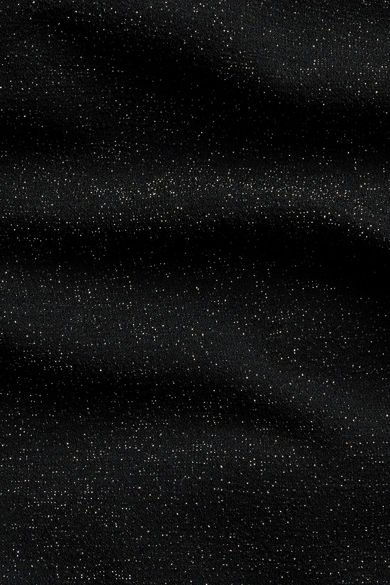 Lähikuva mustasta kankaasta hajanaisella valkoisella glitterillä.