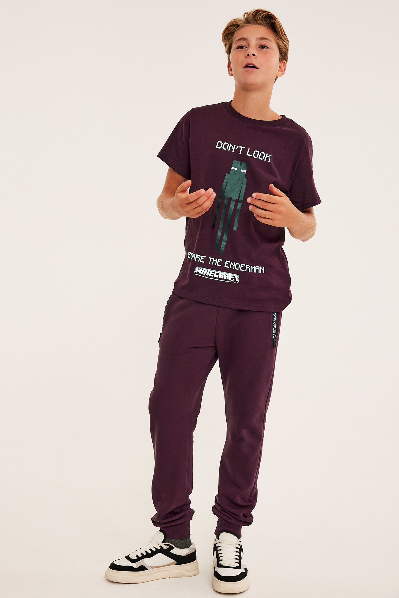 Frontbilde av et barn i plommefarget Minecraft T-skjorte, matchende joggebukse og sneakers.