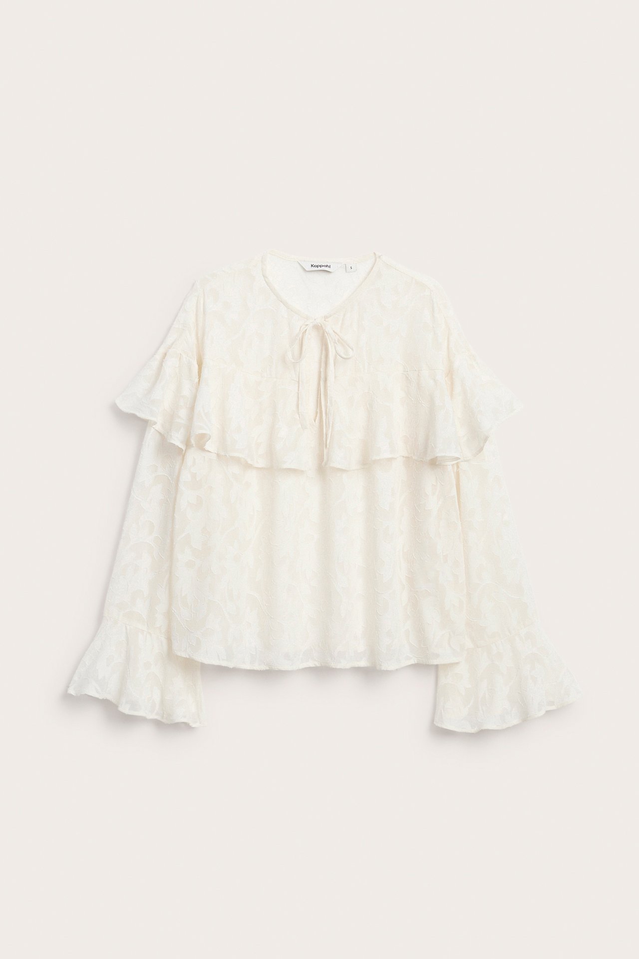 Front, kremhvit bluse med blomstermønster, knytehals, volanger og lange volangermer.