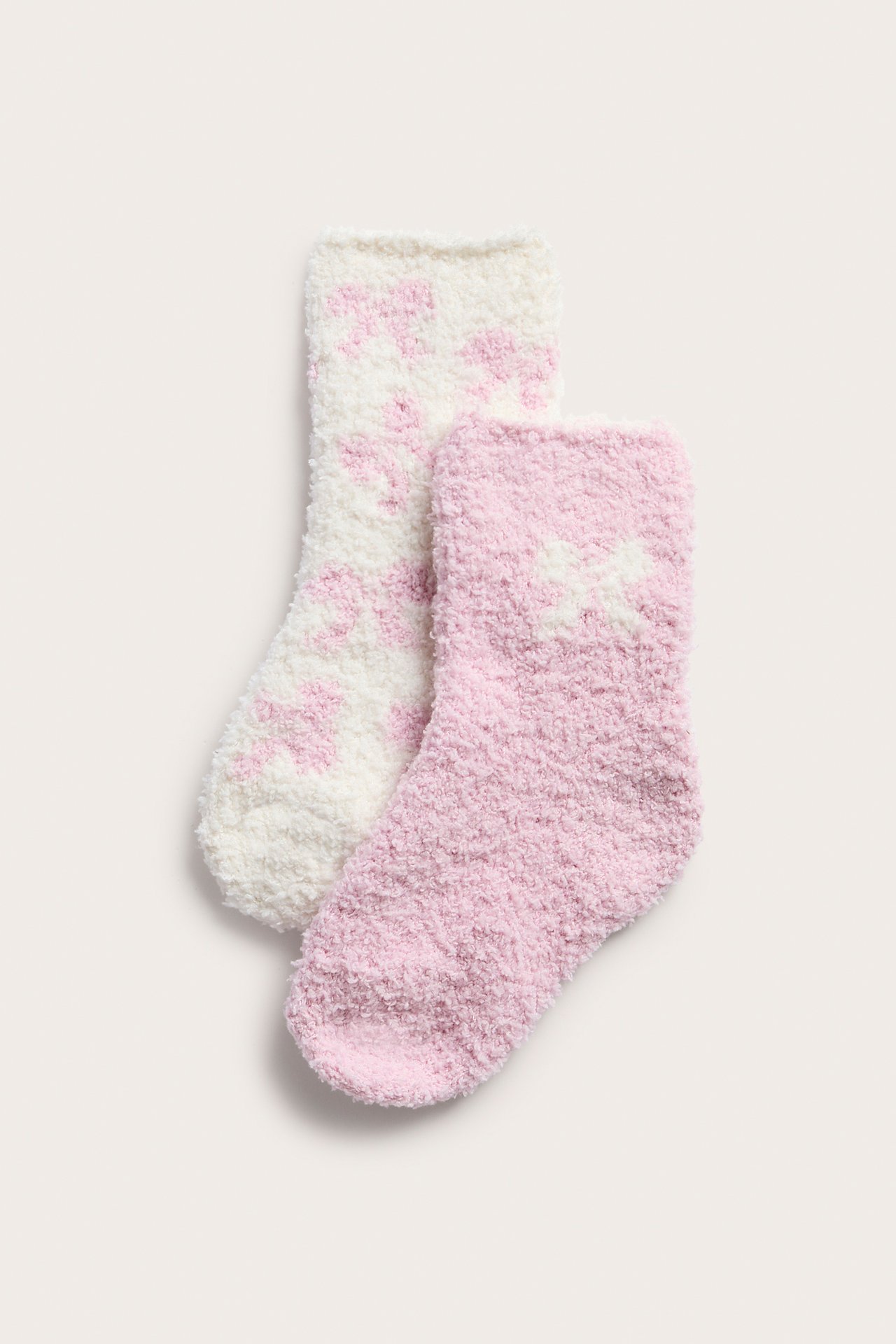 Uppifrån sedd, en rosa fluffig strumpa med vita hjärtan och en vit med rosa hjärtan.