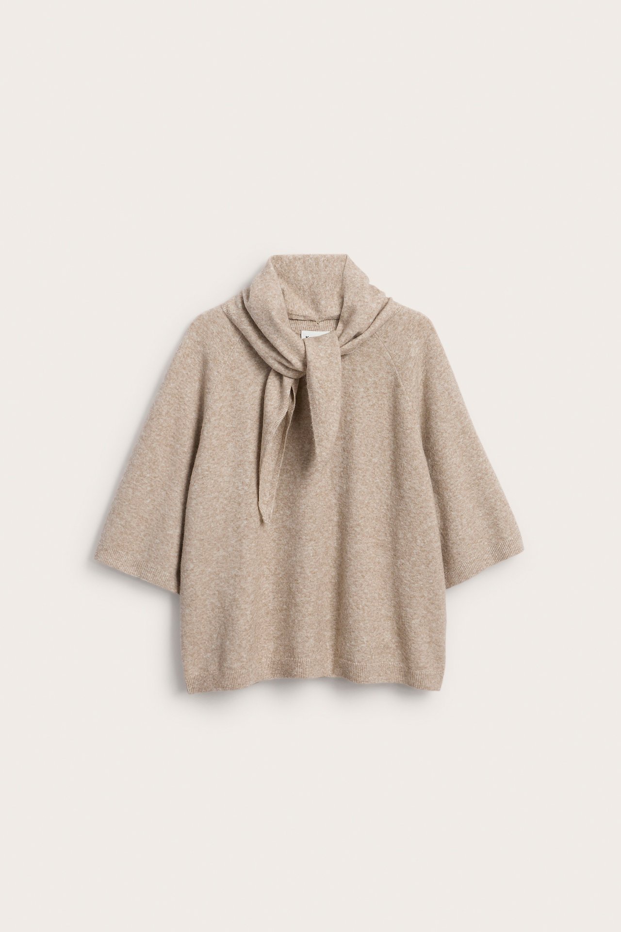 Framsida av en beige stickad topp med vida korta ärmar och integrerad scarfhals.