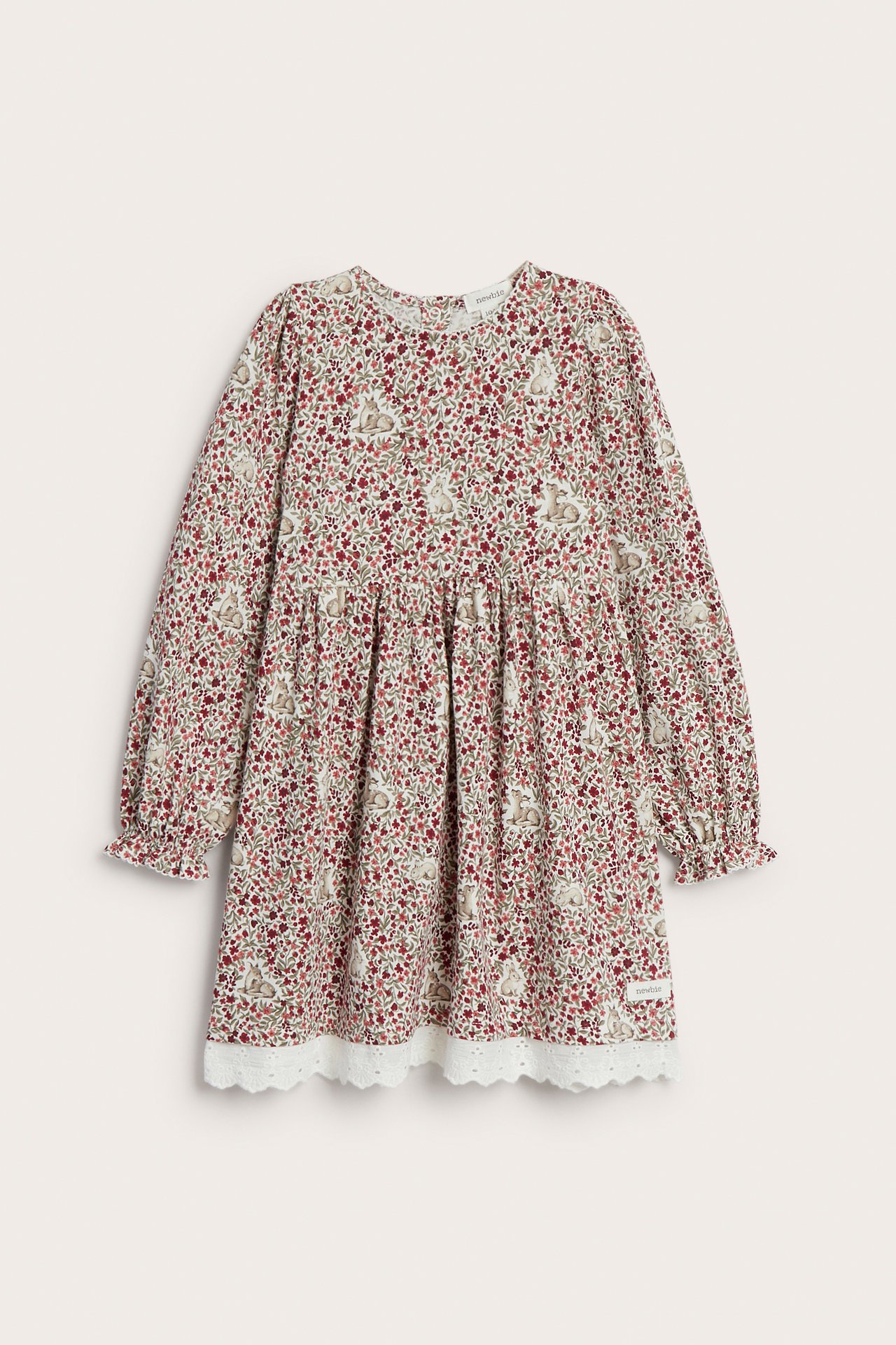 Framsida av en barns långärmade klänning med blommigt och kaninmönster och vit spetskant.