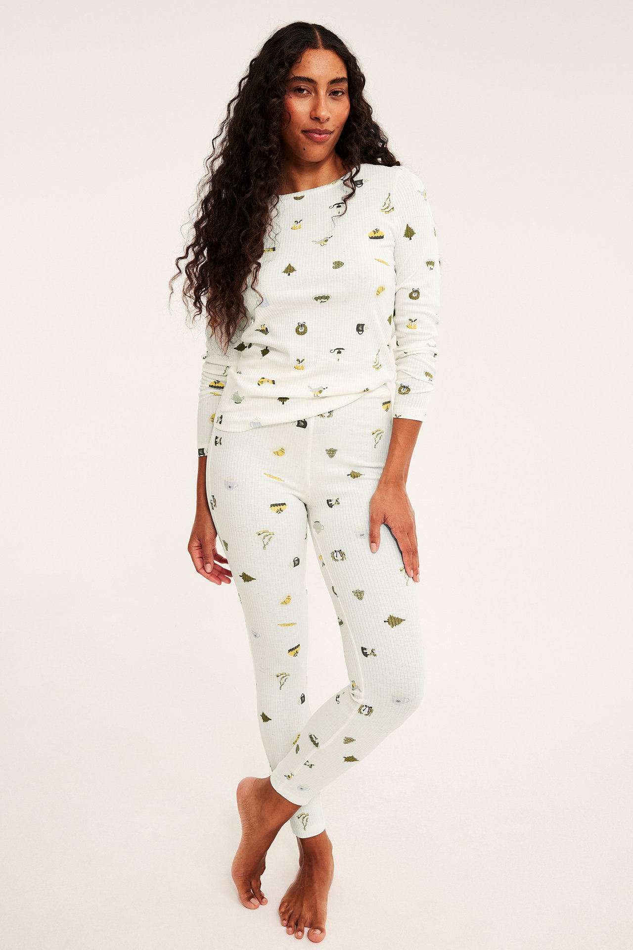 Etukuva naisesta kermanvärisessä ribbipyjamassa luontokuvioilla.
