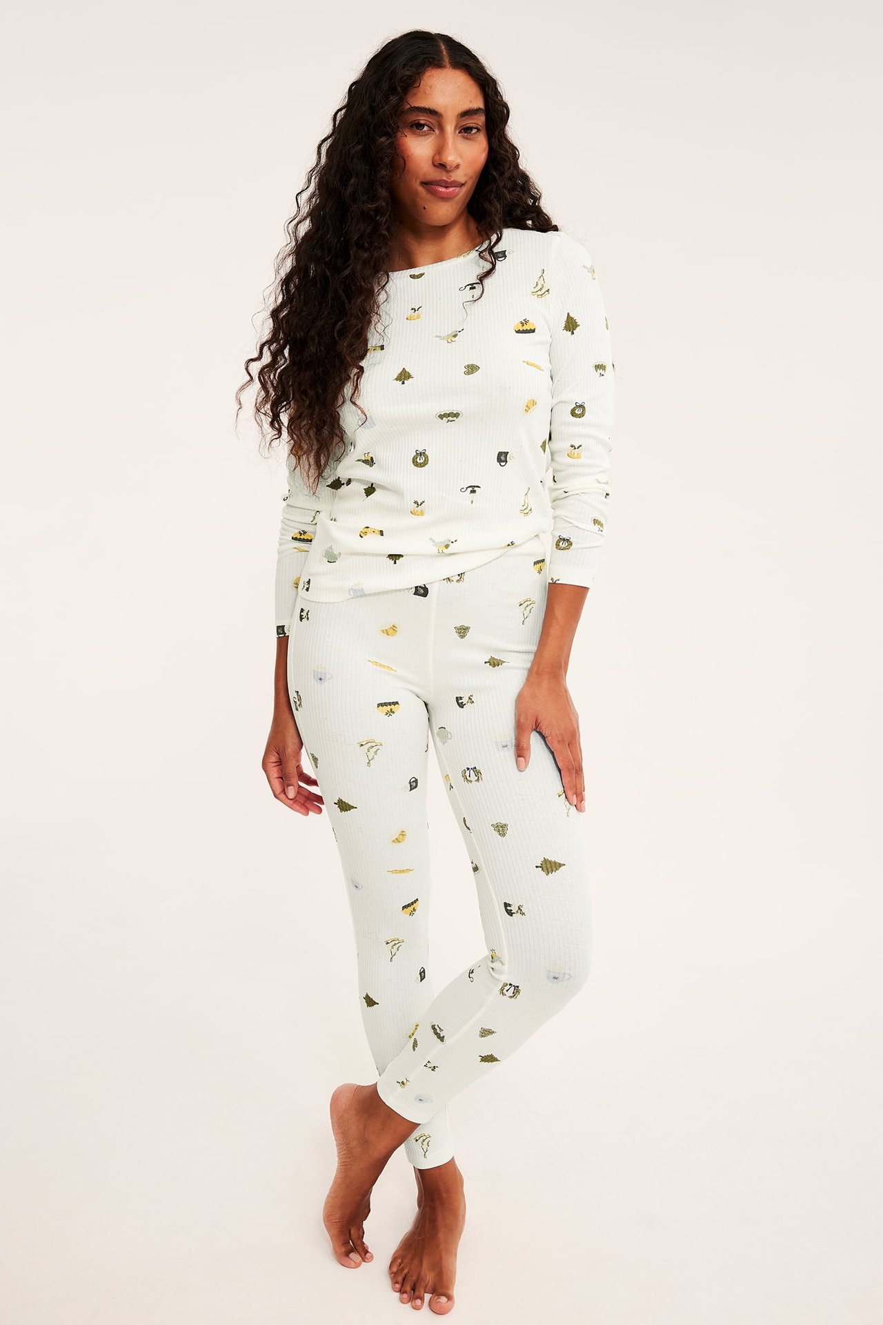 Etukuva naisesta kermanvärisessä ribbipyjamassa luontokuvioilla.