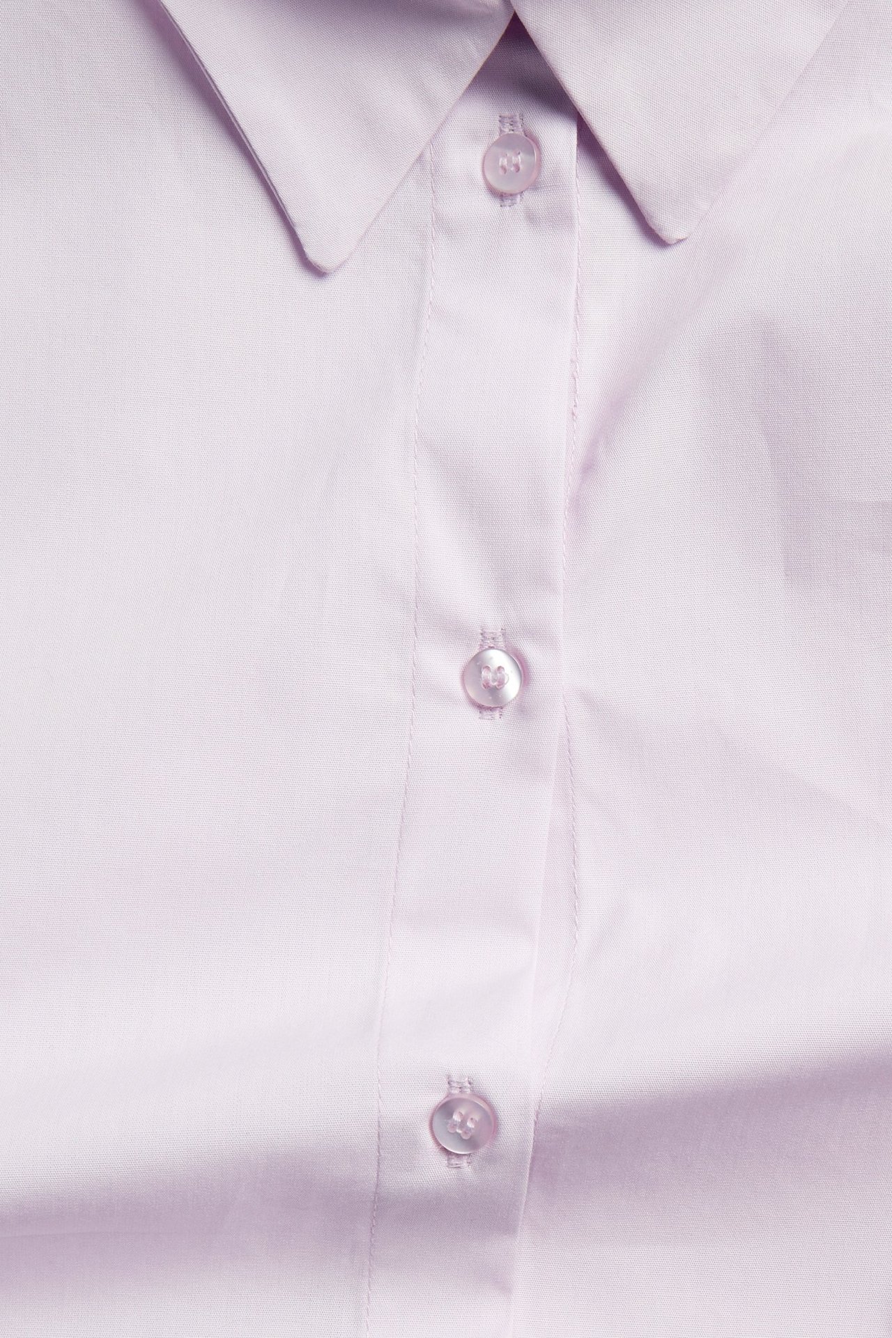 Lähikuva vaaleanliilasta ylisuuresta puuvillapopliinipaidasta, jossa näkyy kaulus ja kolme nappia.