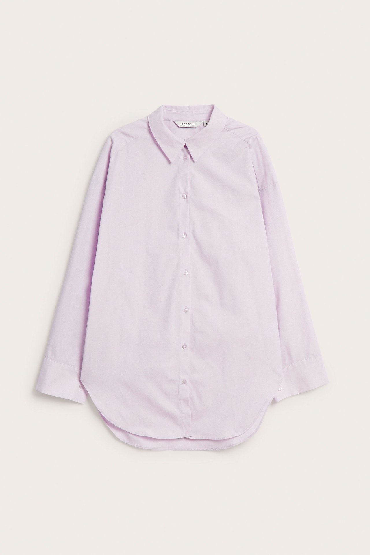 Edestäpäin vaaleanliila ylisuuri puuvillapopliinipaita pitkillä hihoilla, napeilla ja pyöreällä helmalla.