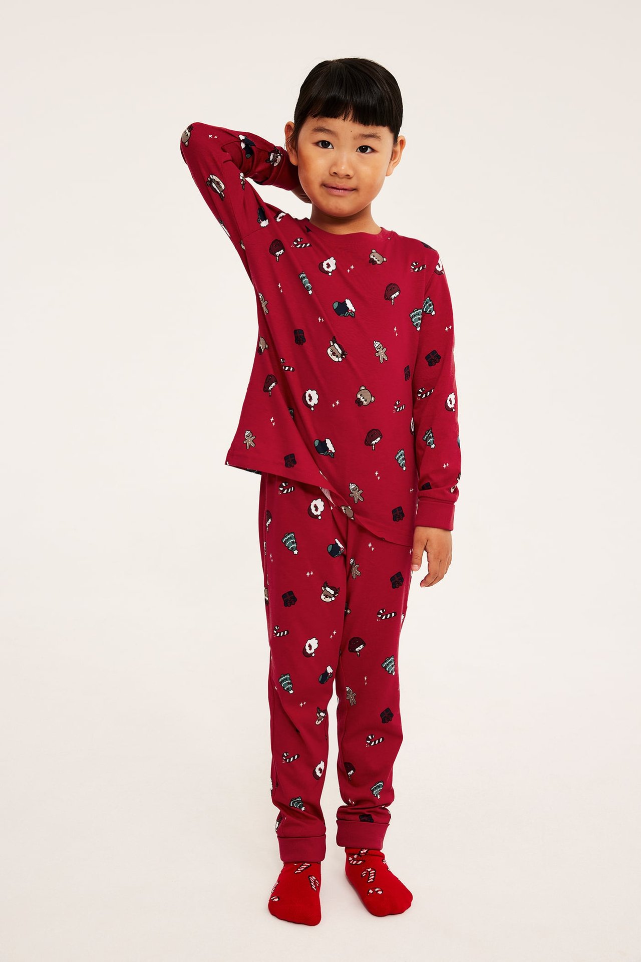Framifrån, barn i rött julmönstrat pyjamasset med matchande strumpor.