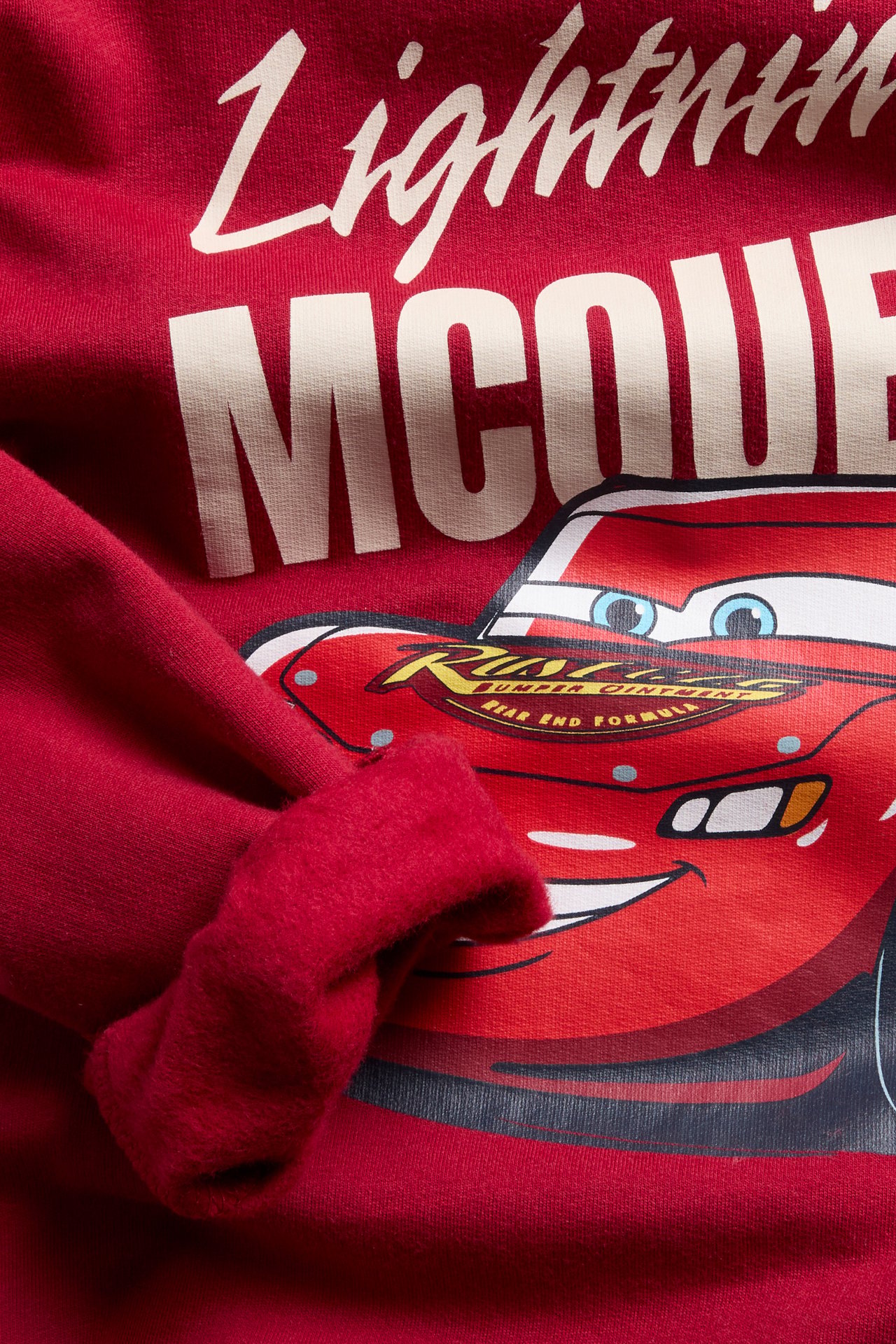 Nærbilde forfra av en rød barnesweatshirt med Lynet McQueen-trykk.