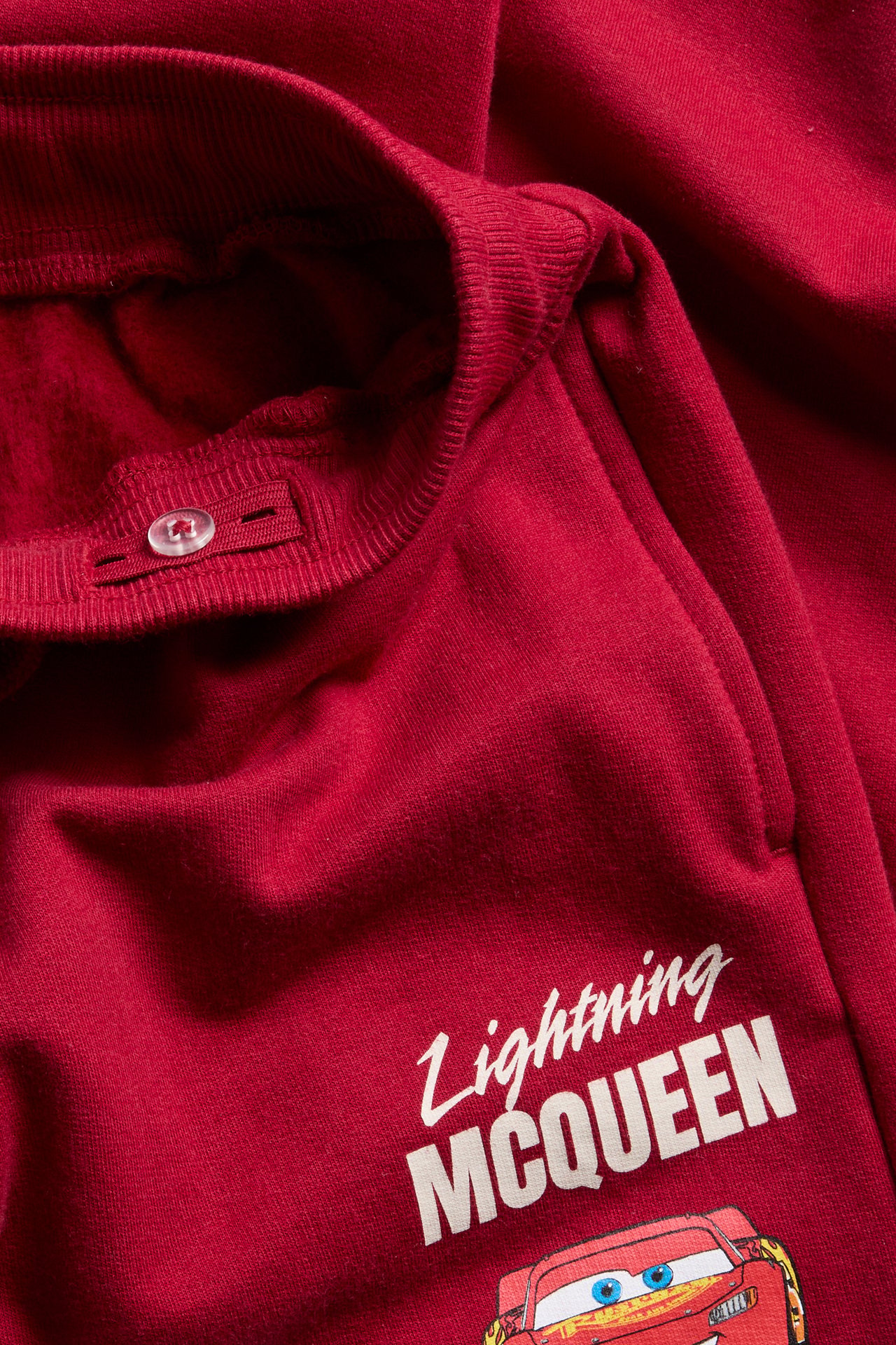 Nærbilde av røde Lightning McQueen-joggebukser til barn med justerbar knapplinning.