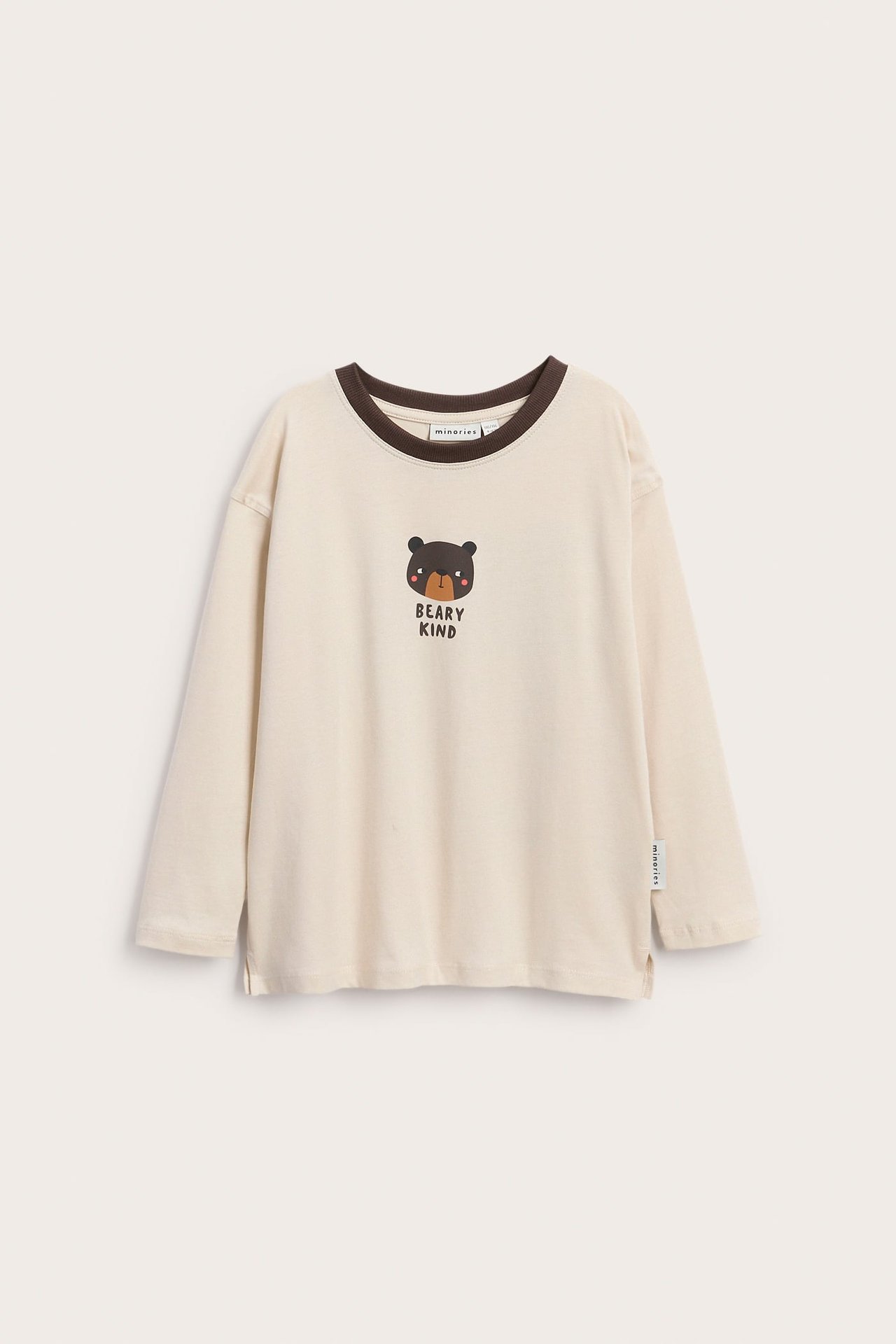 Edestä näkymä lasten luonnonvalkoisesta pitkähihaisesta t-paidasta ruskealla kauluksella ja 'BEARY KIND' karhuprintillä.