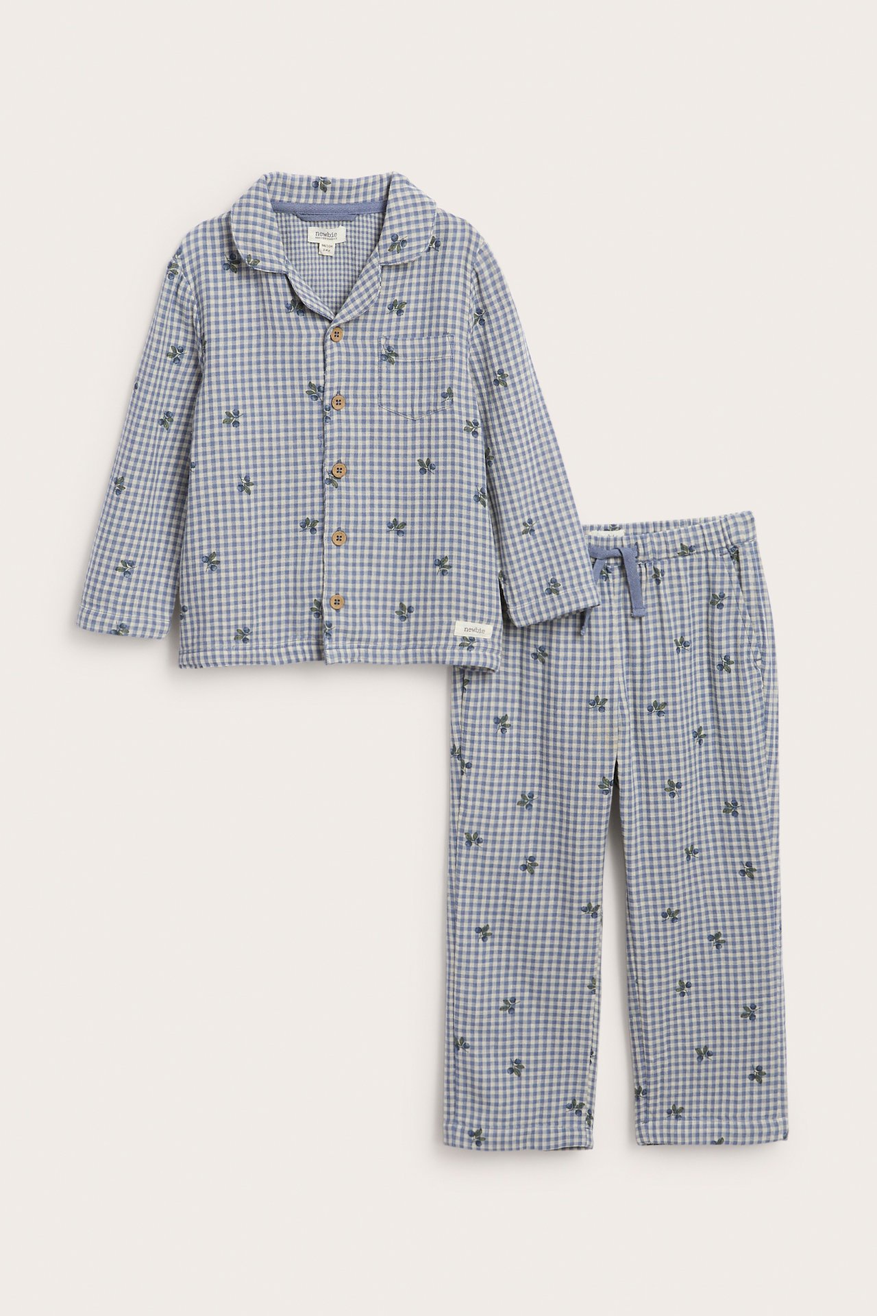 Edestä: Lasten siniruudullinen pyjama hedelmäkuviolla, kauluspaita ja kiristysnyörihousut.