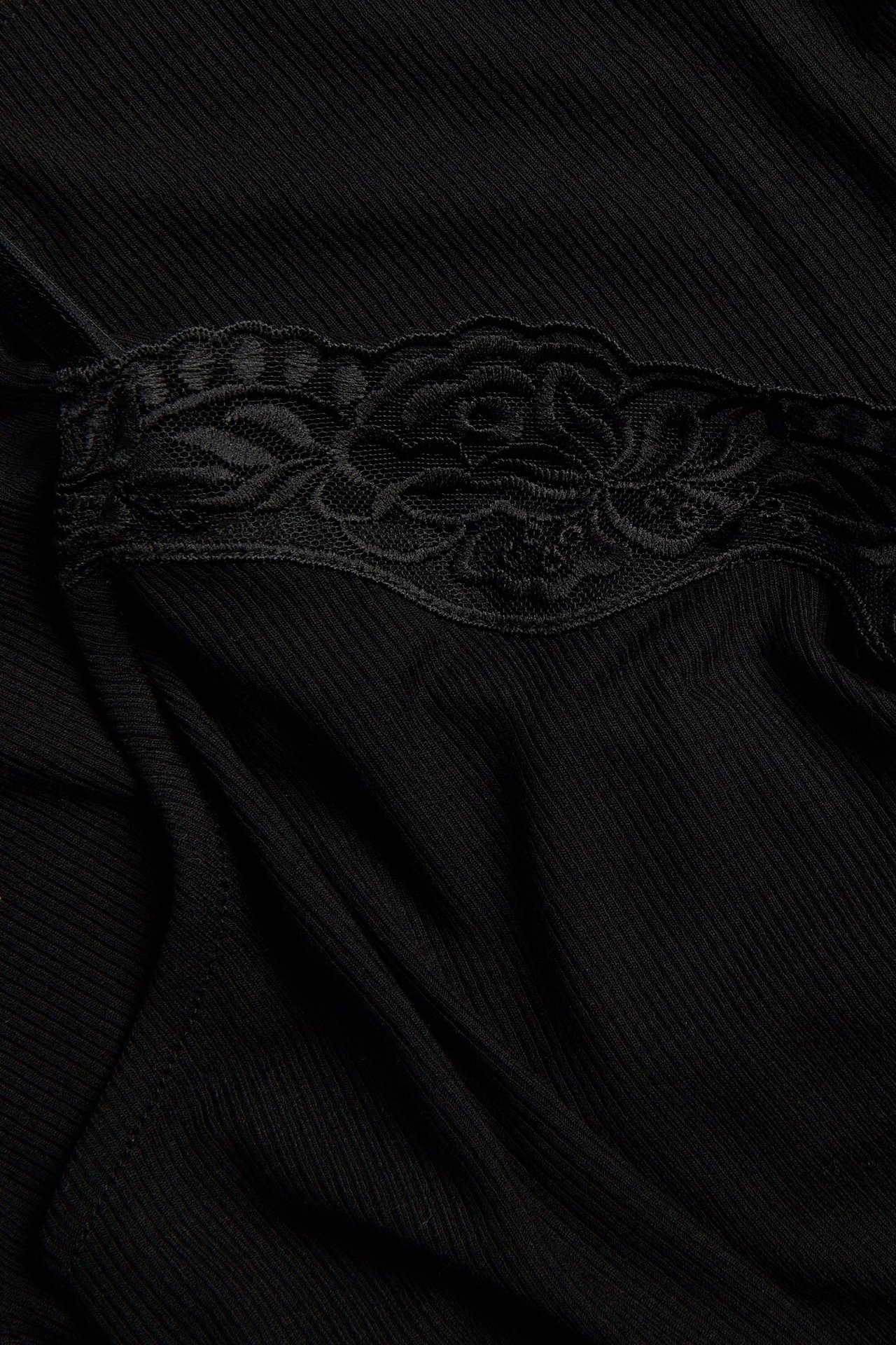 Lähikuva mustasta ribbineuleisesta topista, jossa musta pitsireuna.