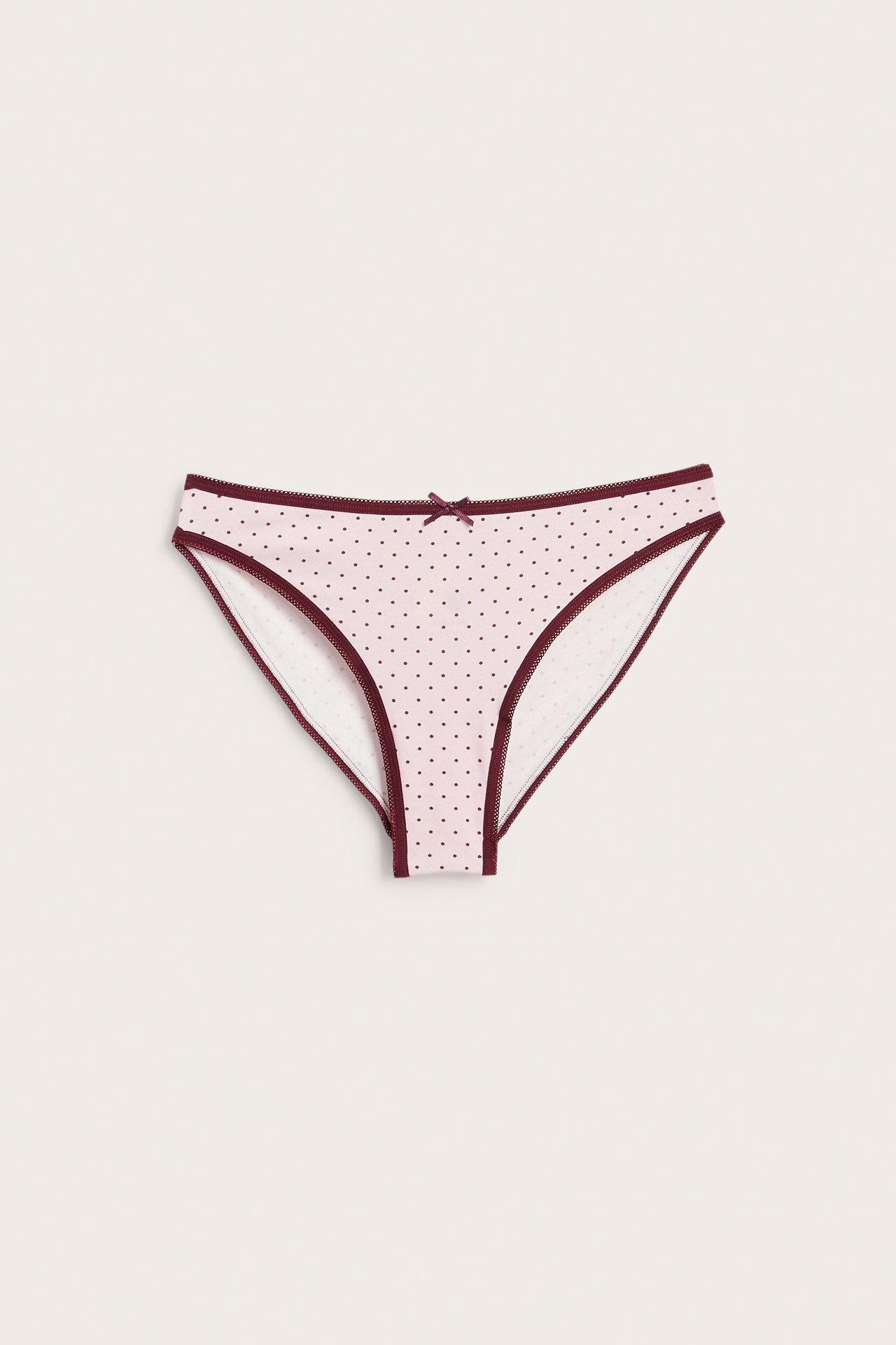Widok z przodu: damskie jasnoróżowe figi bikini w kropki z bordowym obszyciem i kokardką.