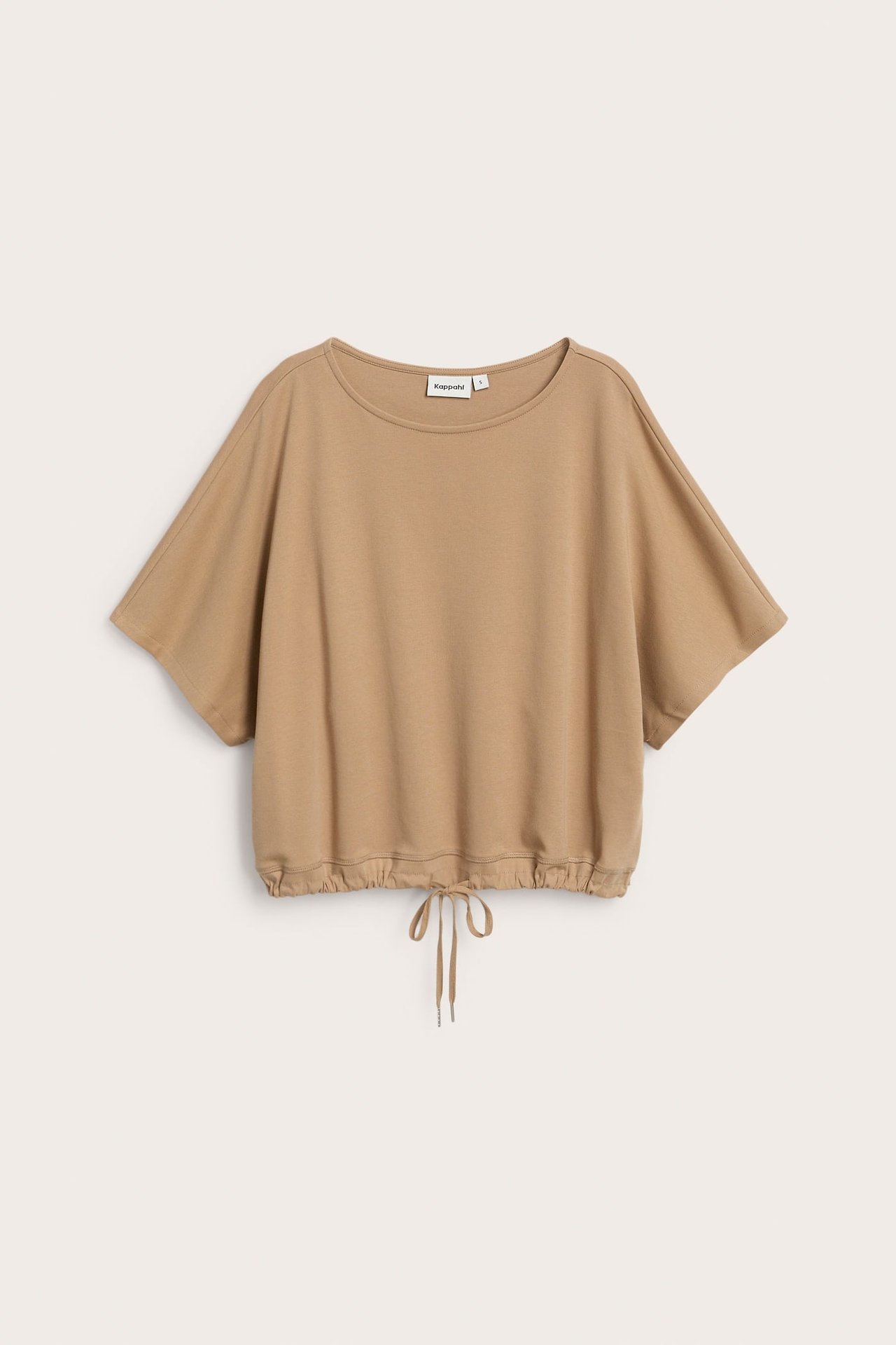 Edestä kuvattu oversized beige lyhythihainen puuvillatoppi kiristysnauhalla helmassa.