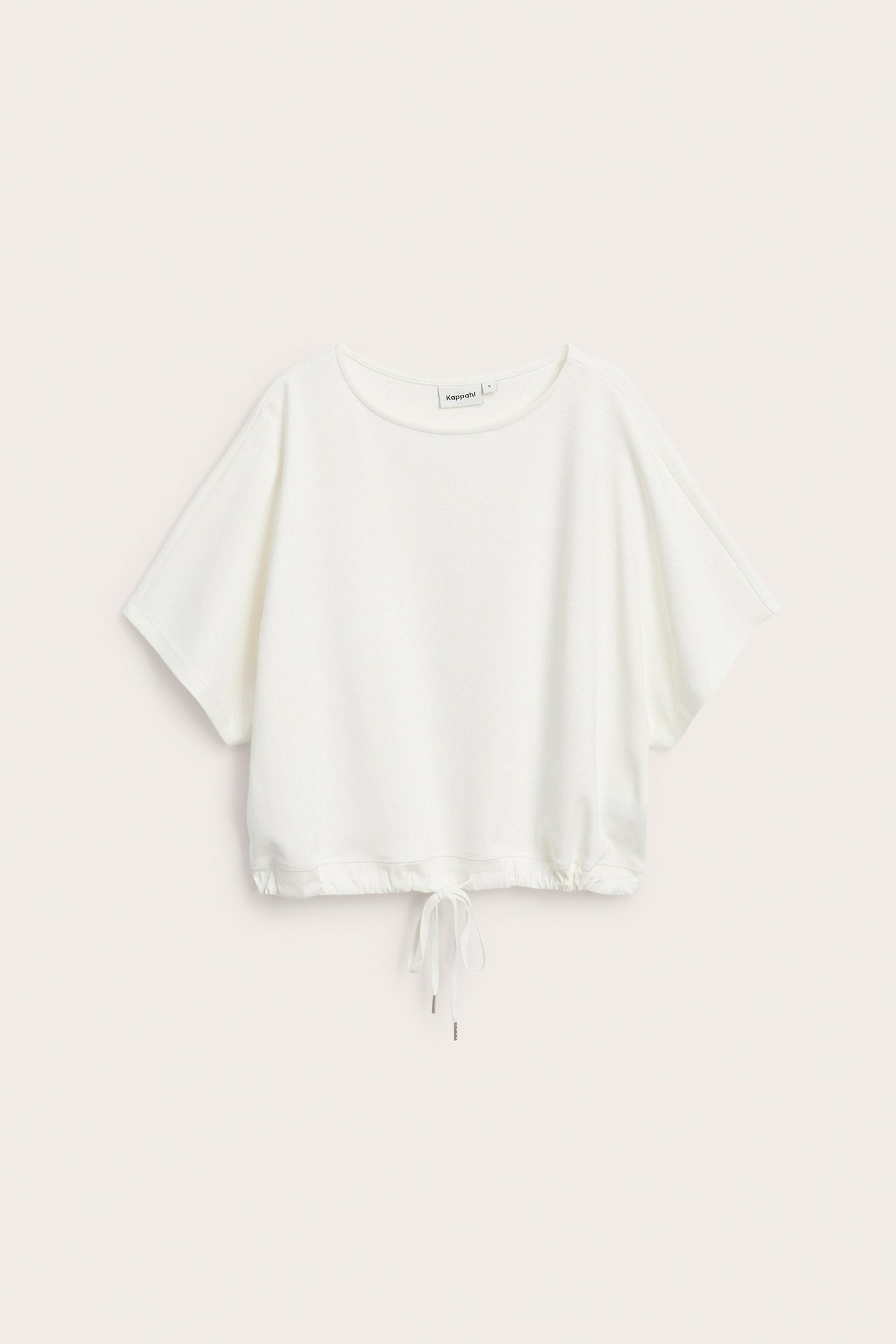 Widok z przodu: kremowa, bawełniana, oversize'owa bluzka z krótkim rękawem i troczkami u dołu.