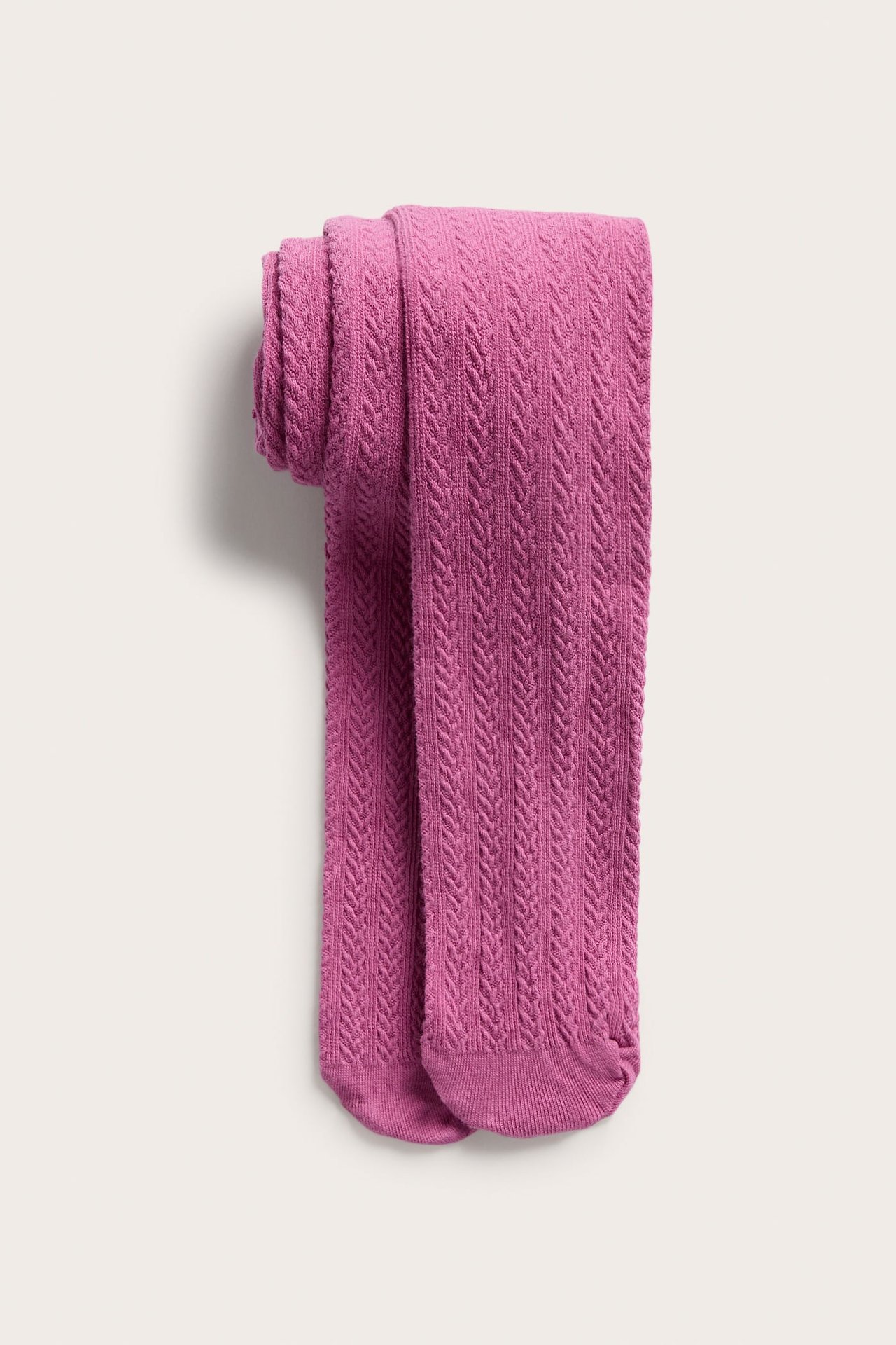Ylhäältä näkymä fuchsianvärisistä palmikkoneulossukkahousuista, rullattuina.