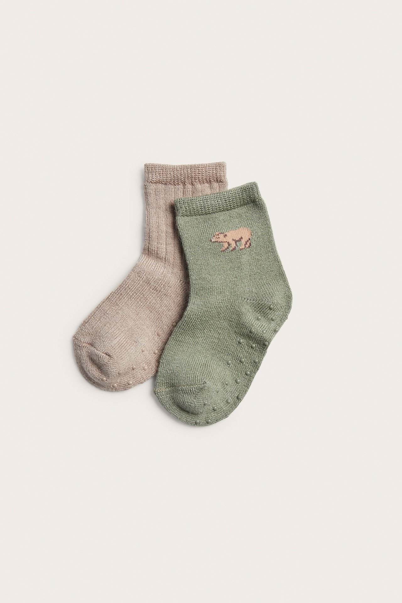 Vihreä vauvansukka karhubrodeerauksella ja liukuesteillä sekä beige vauvansukka.