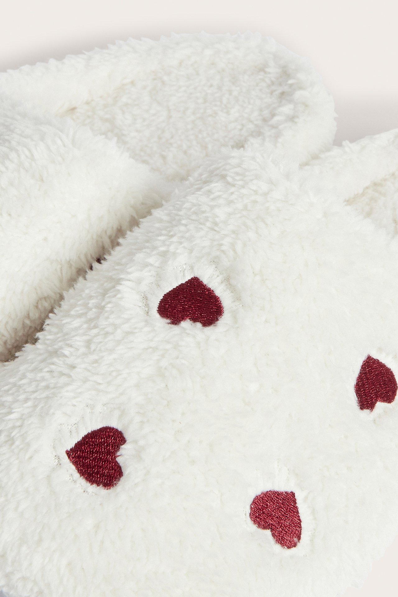 Närbild av vita fluffiga strumpor med broderade röda hjärtan.