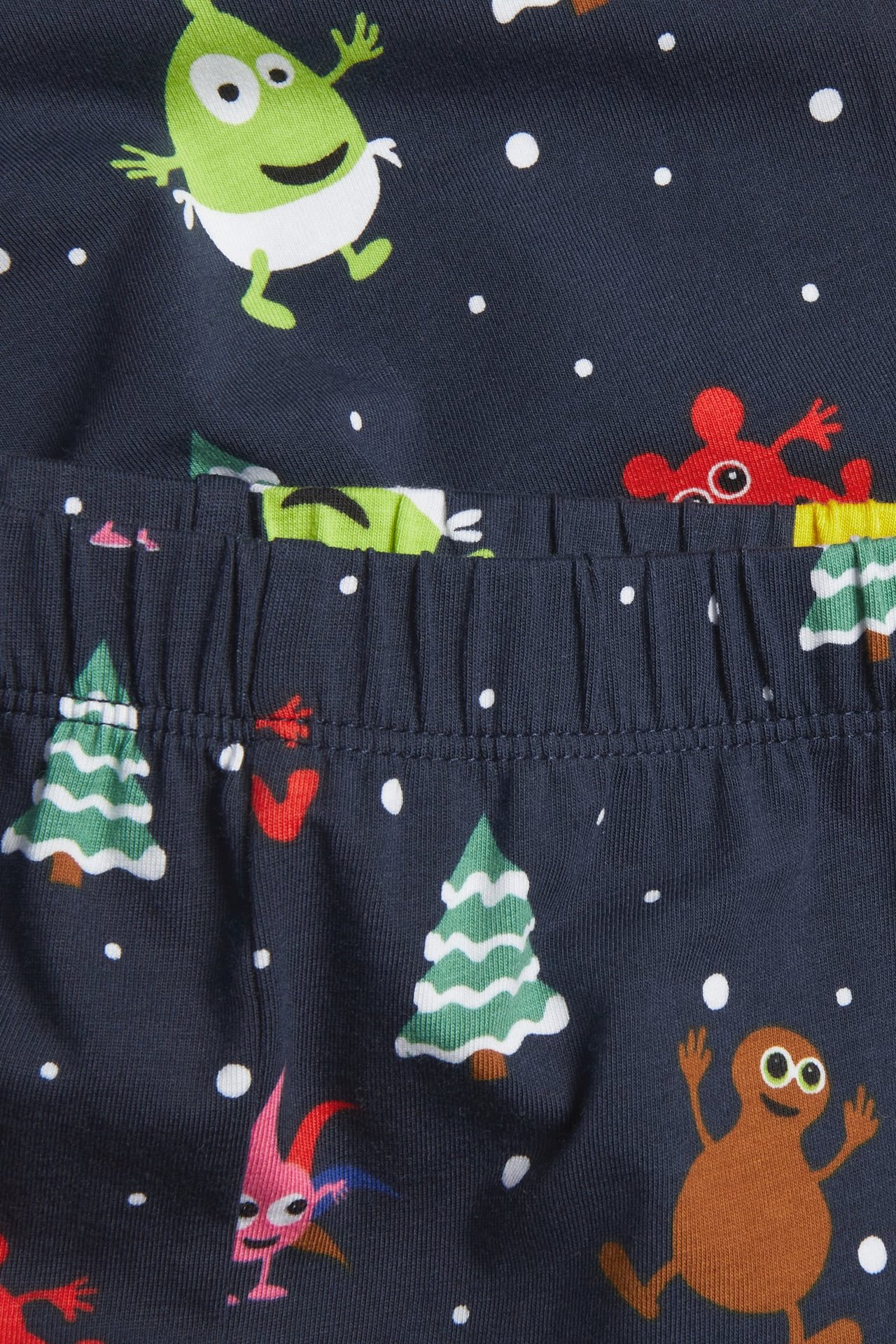 Närbild på mörkblå pyjamasbyxor för barn med resår i midjan och tecknat jultryck.