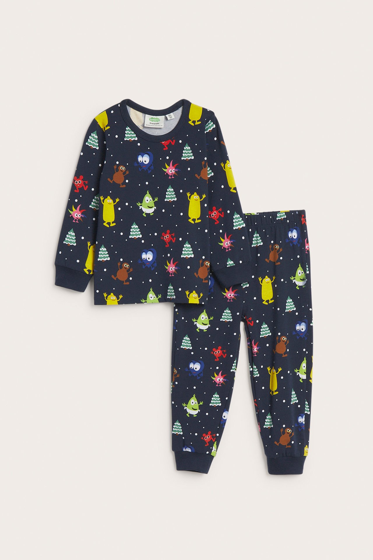 Framifrån, barnpyjamas i mörkblått med färgglatt monster- och julgransmönster.