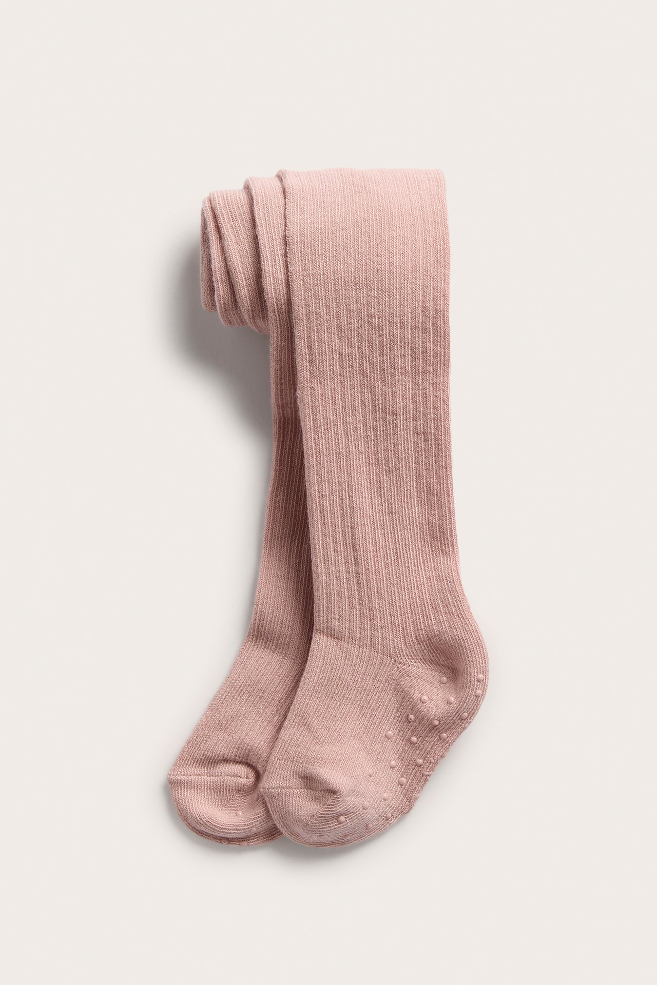 Ovenfra, rosa ribbestrikket babystrømpebukse med antiskli-knotter på sålene.