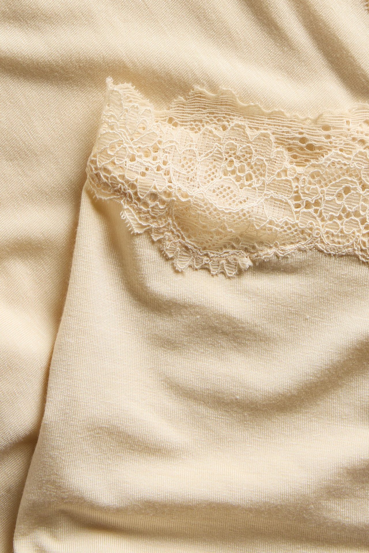 Nærbilde av beige modal boxertruse med blondekantet midje.