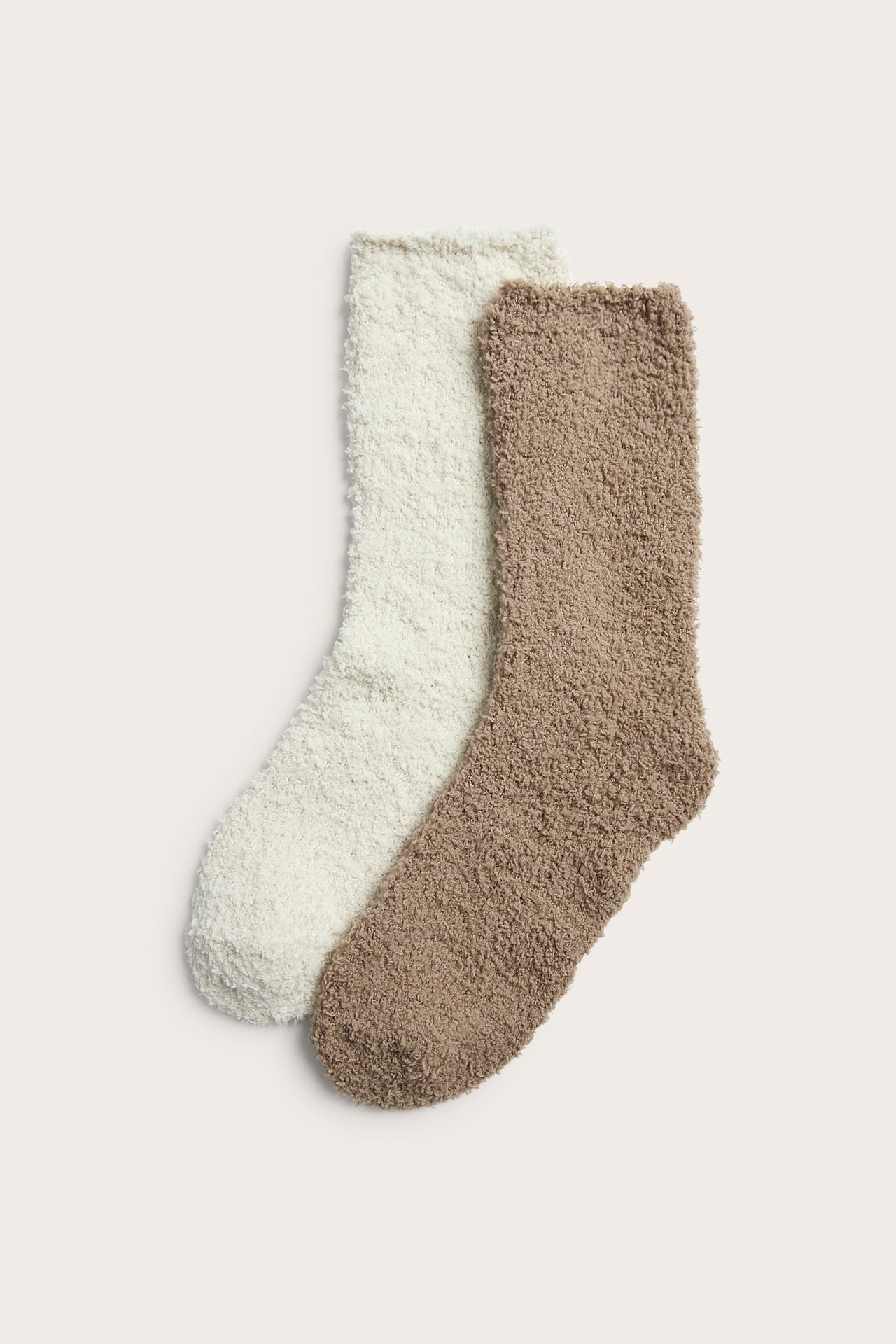 Flat lay av två fluffiga strumpor, en benvit och en ljusbrun.