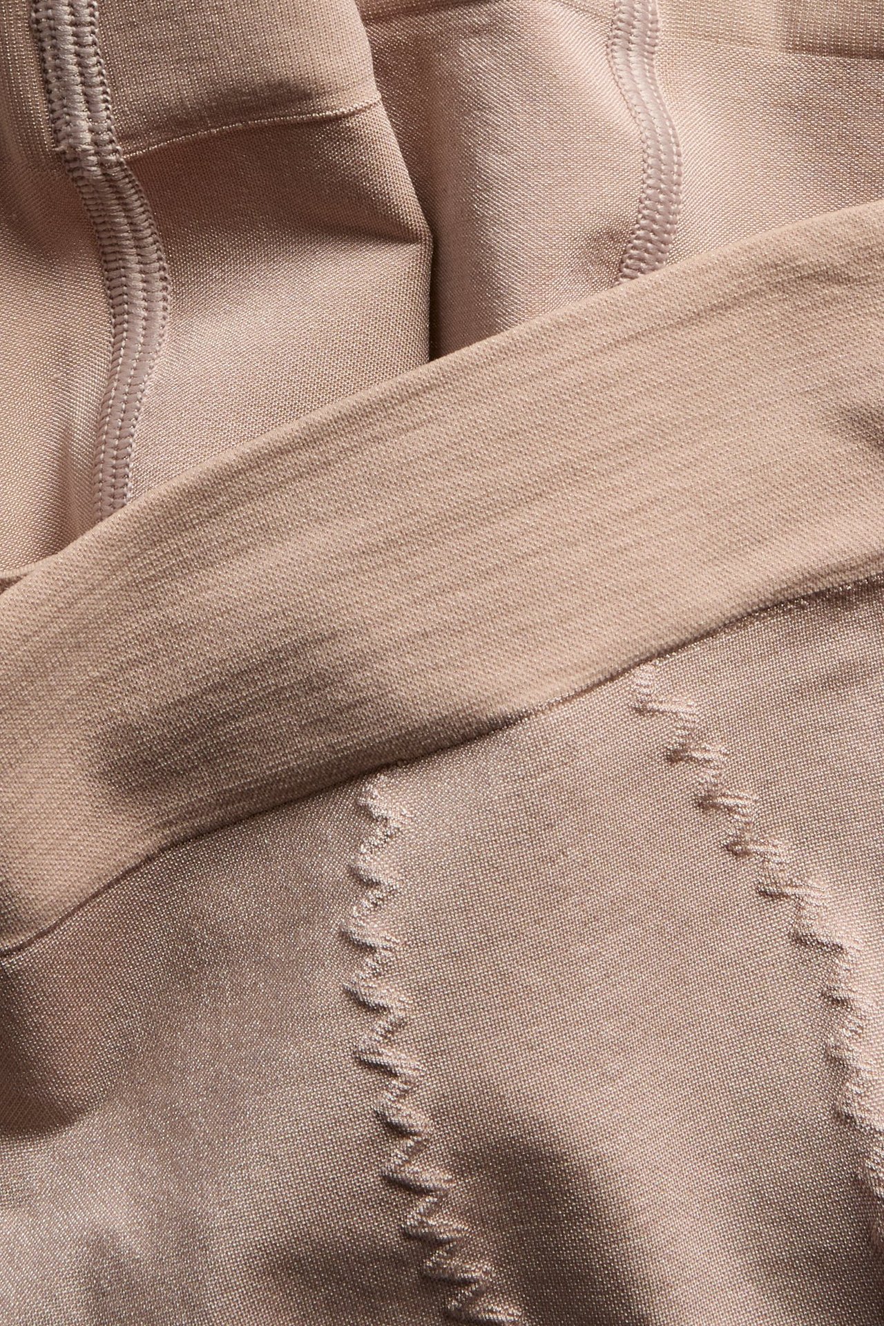 Nærbilde av beige sømløse shapingshorts med høyt liv, støttende sikksakksømmer og glatt linning.